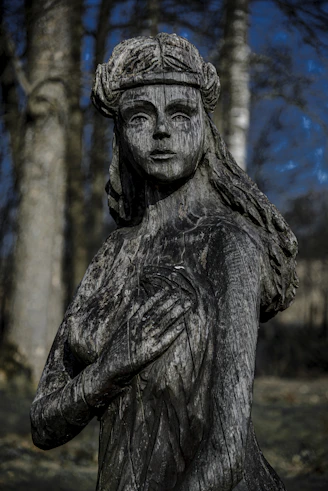 Wooden sculpture of a woman with hands on chest