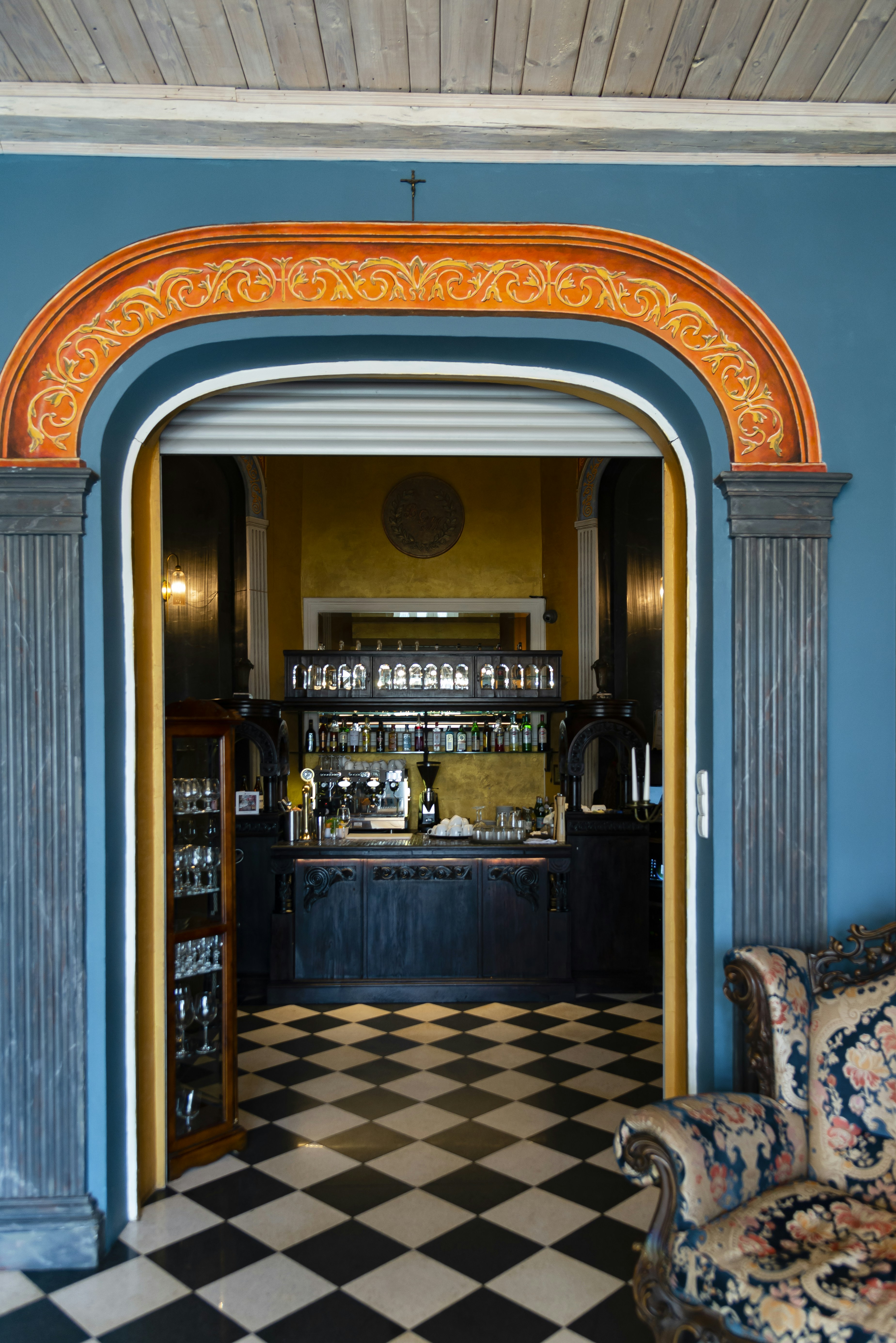 Der verzierte Türrahmen führt zu einer Bar mit karierten Boden.