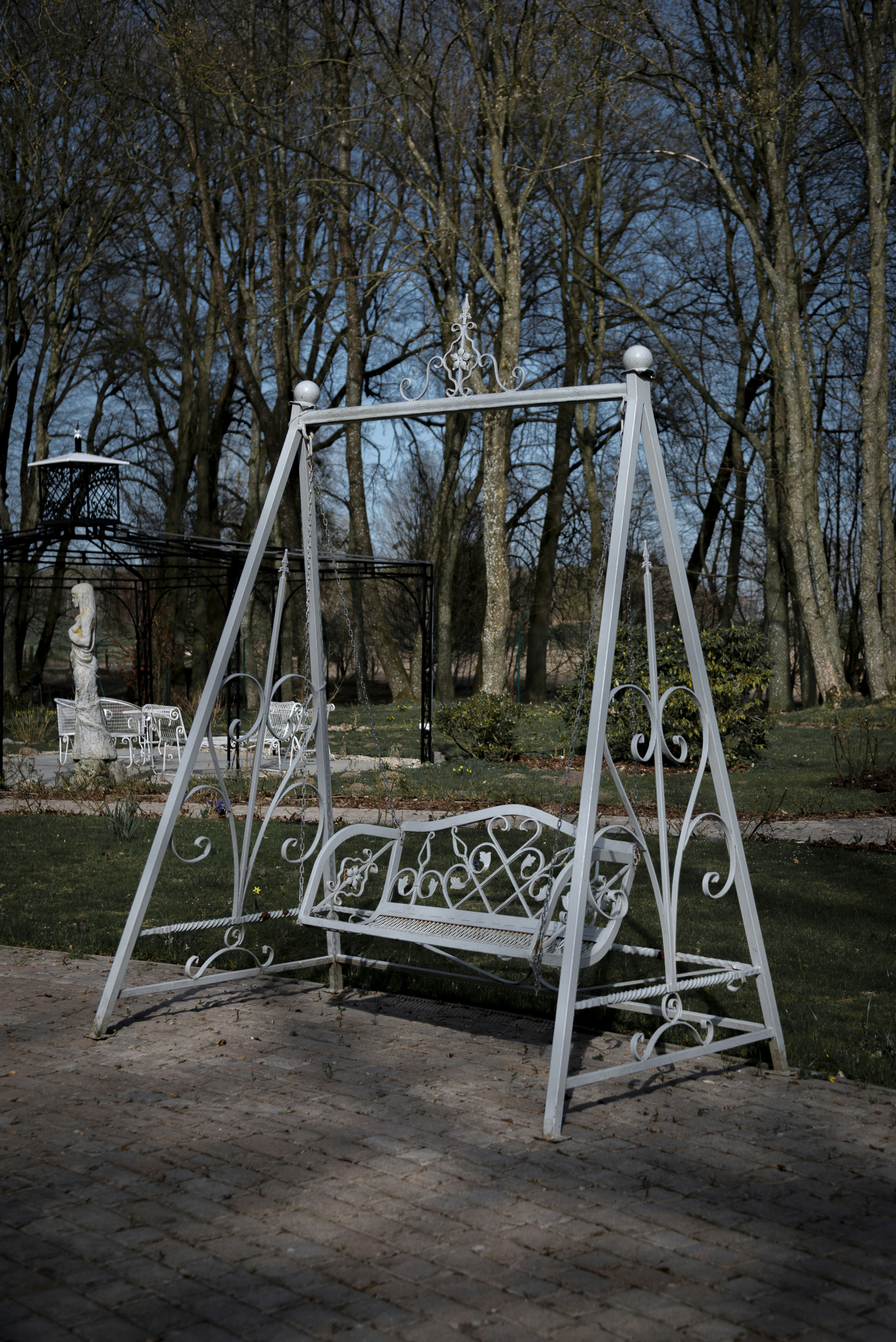 Eine weiße Metallschaukel in einem Park.