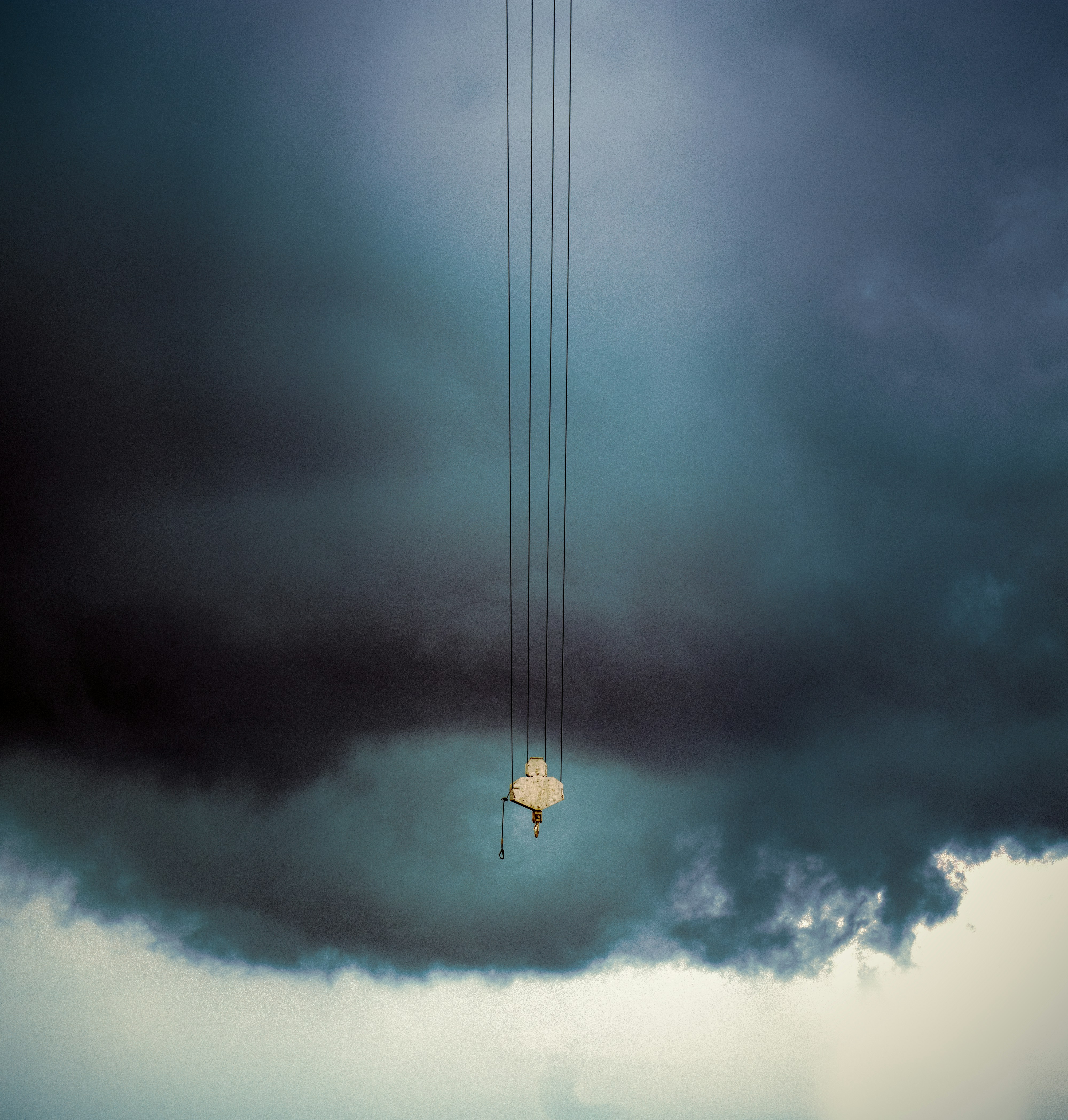 A small object hangs from wires against a stormy sky