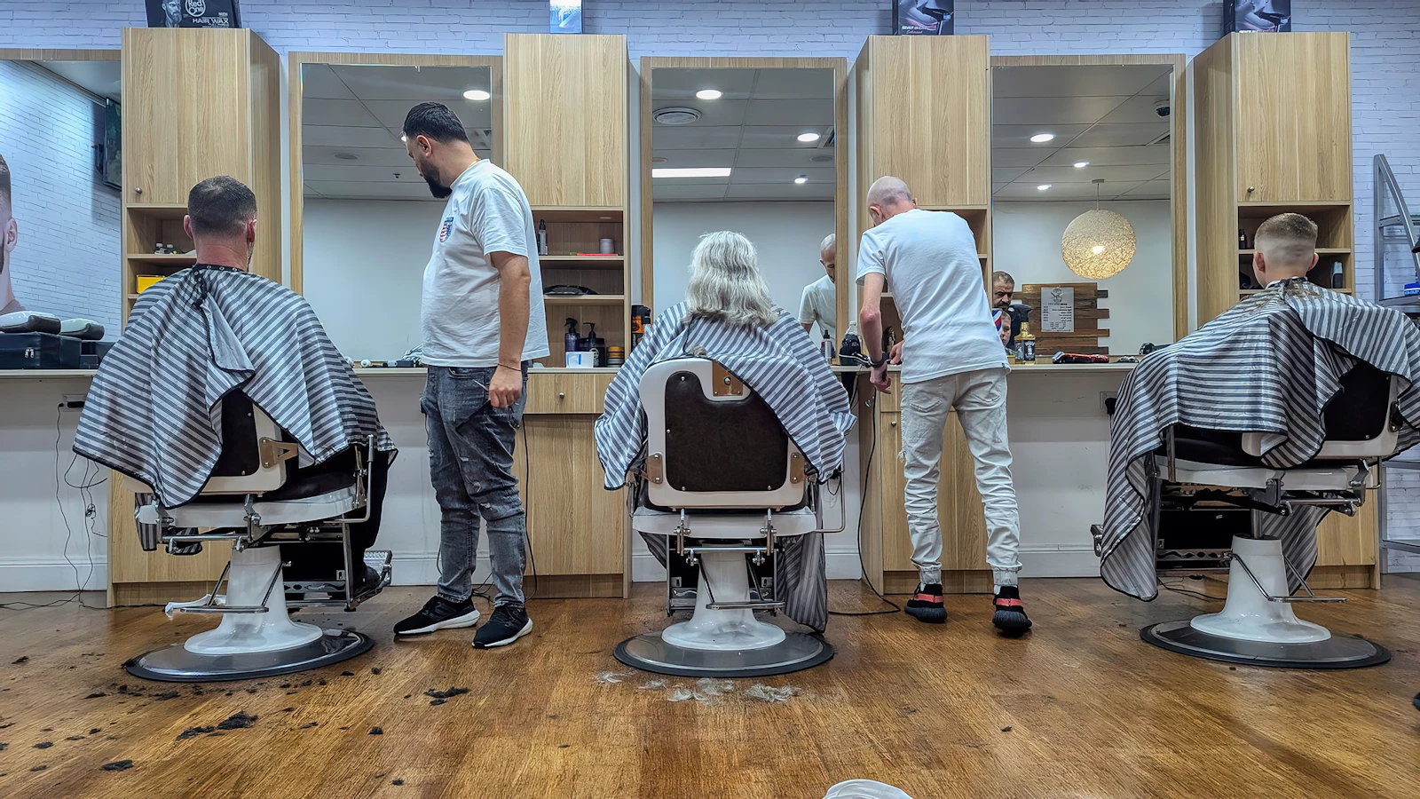 Modern berber salonunda aynı anda birden fazla koltukta tıraş hizmeti