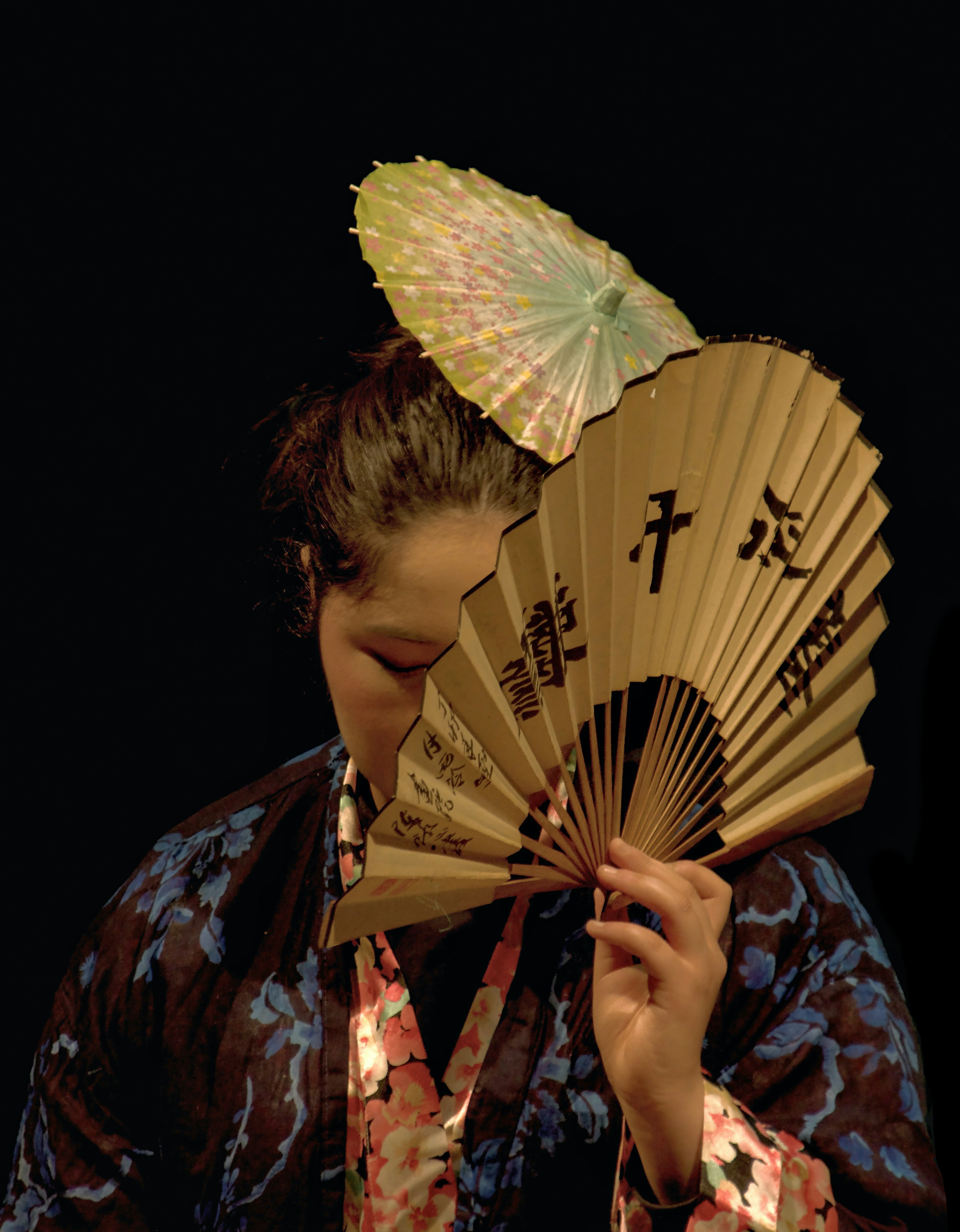 Woman in kimono holding a fan over her face