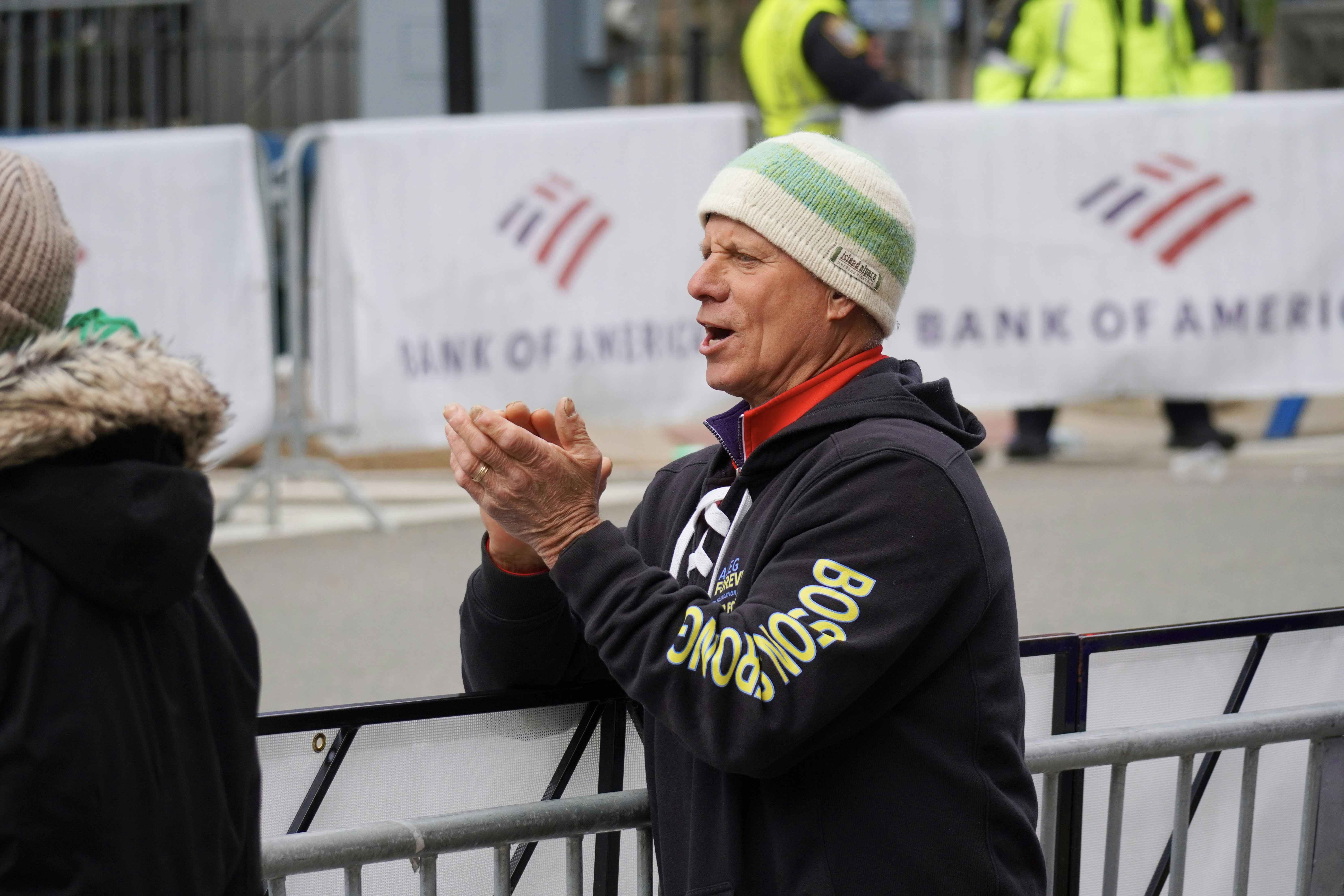 Man in beanie and hoodie claps hands near barrier