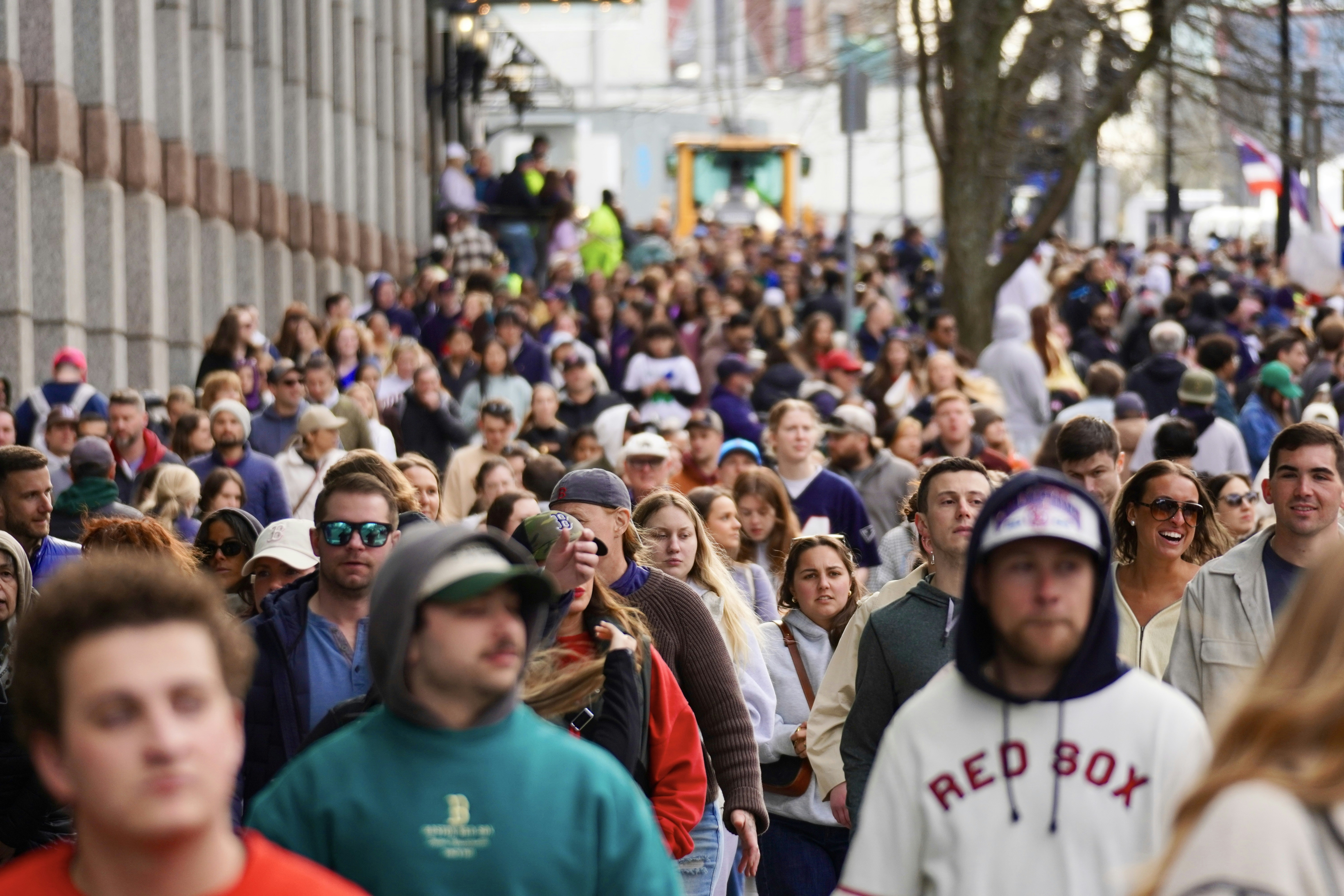A large crowd of people walking down a city street.