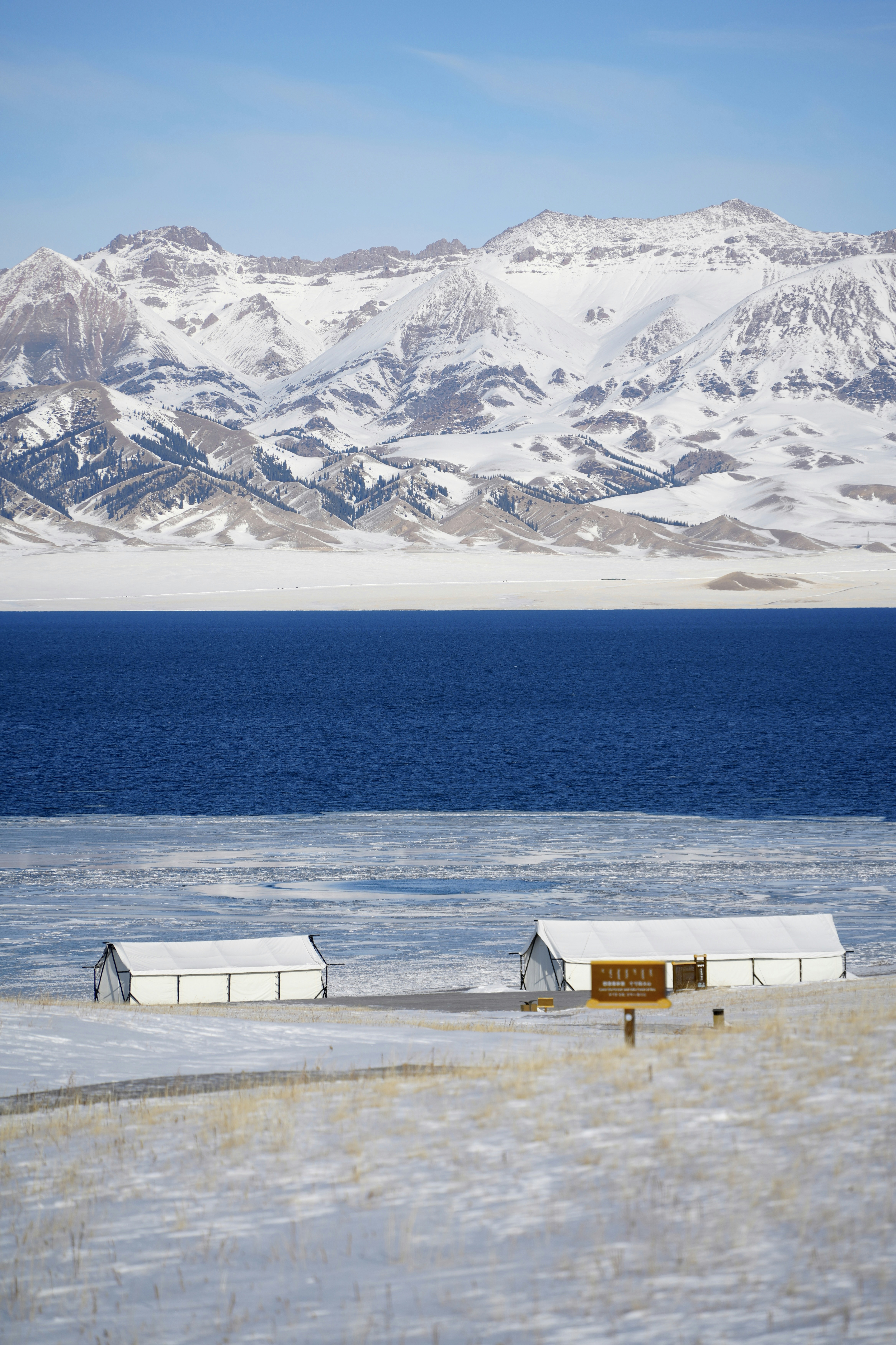 Paisagem nevada com prédios brancos à beira de um lago azul.
