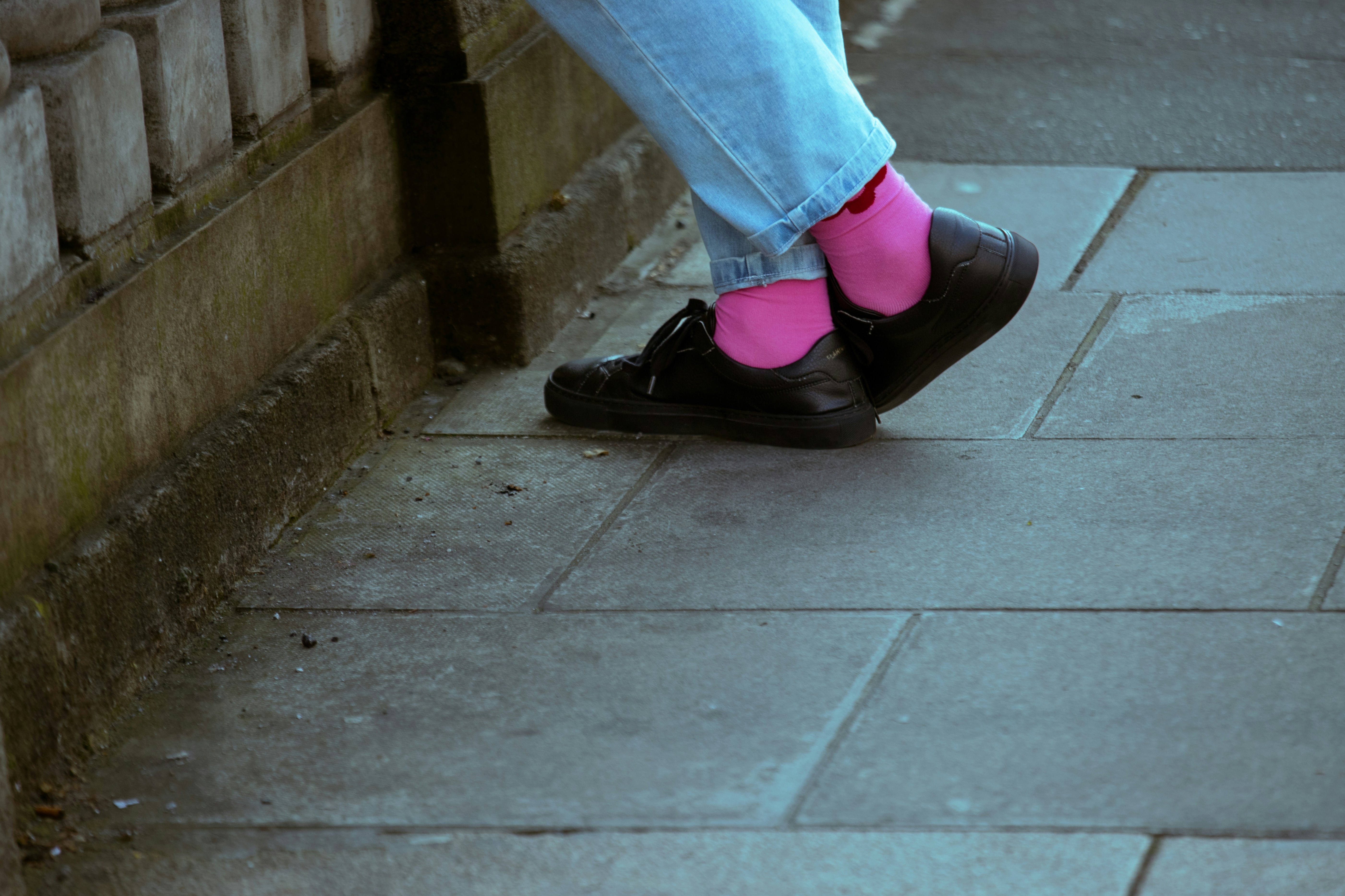 Person wearing pink socks and black shoes on pavement