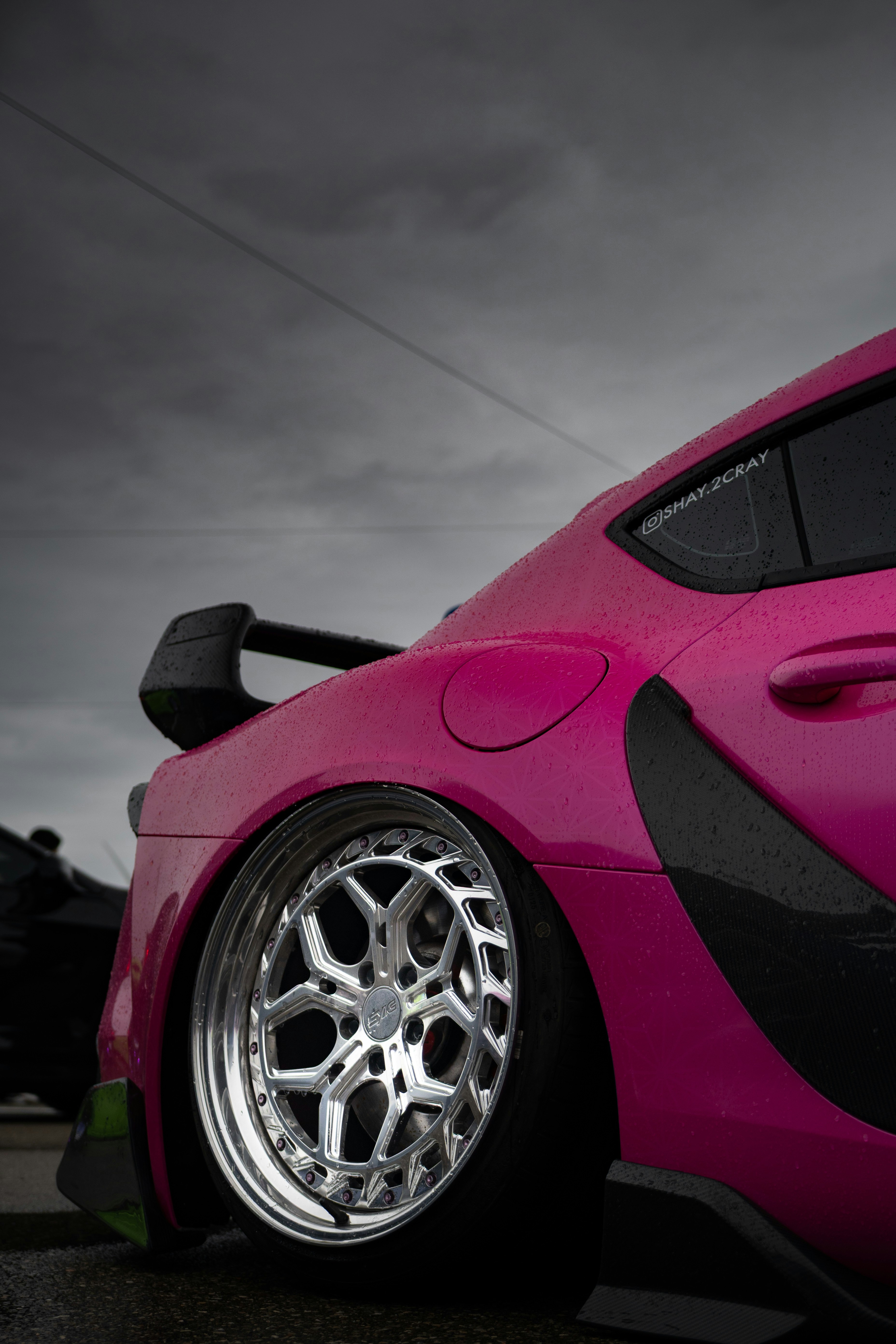 Close-up of a pink sports car with custom wheels.