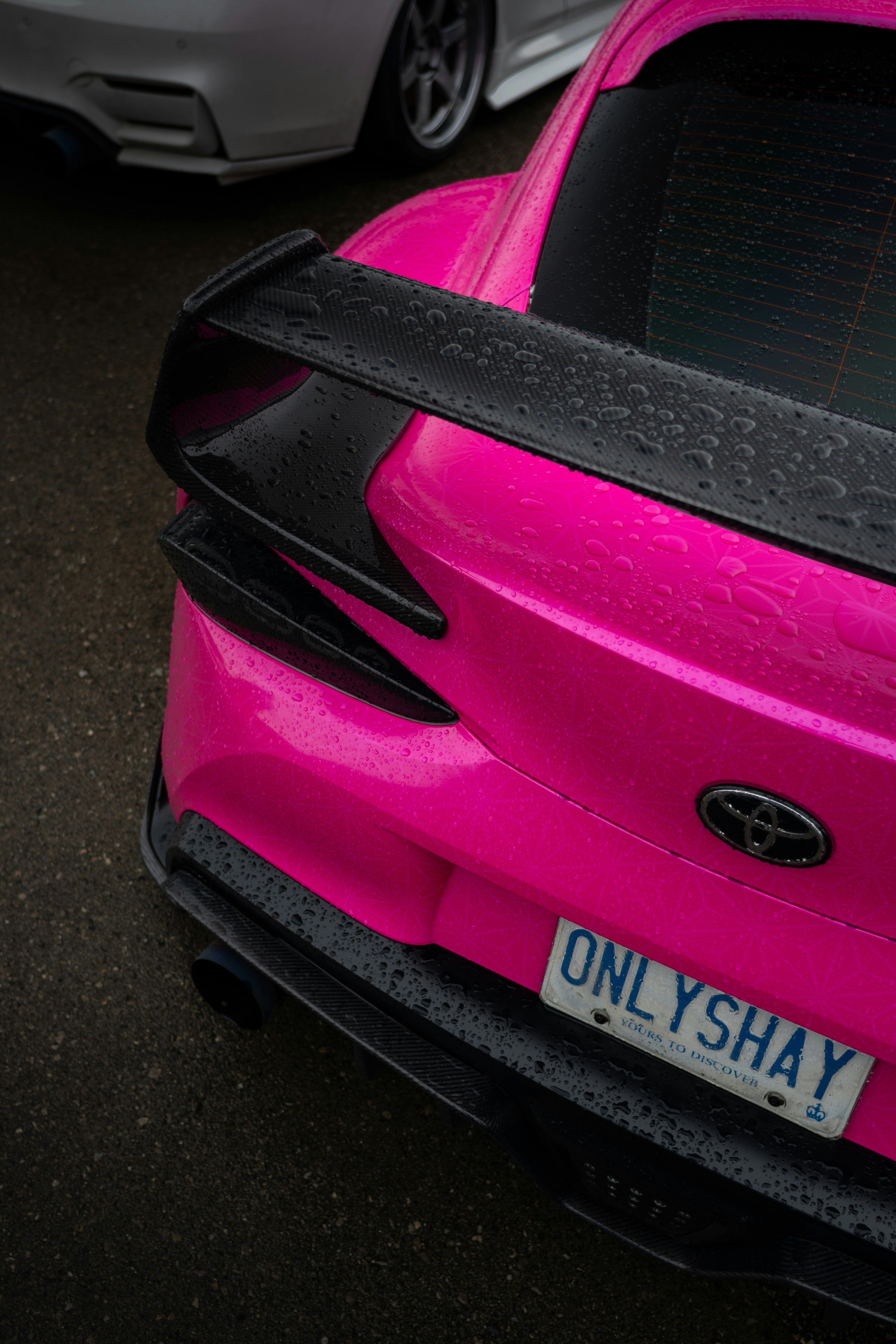 Bright pink car with black spoiler and license plate.