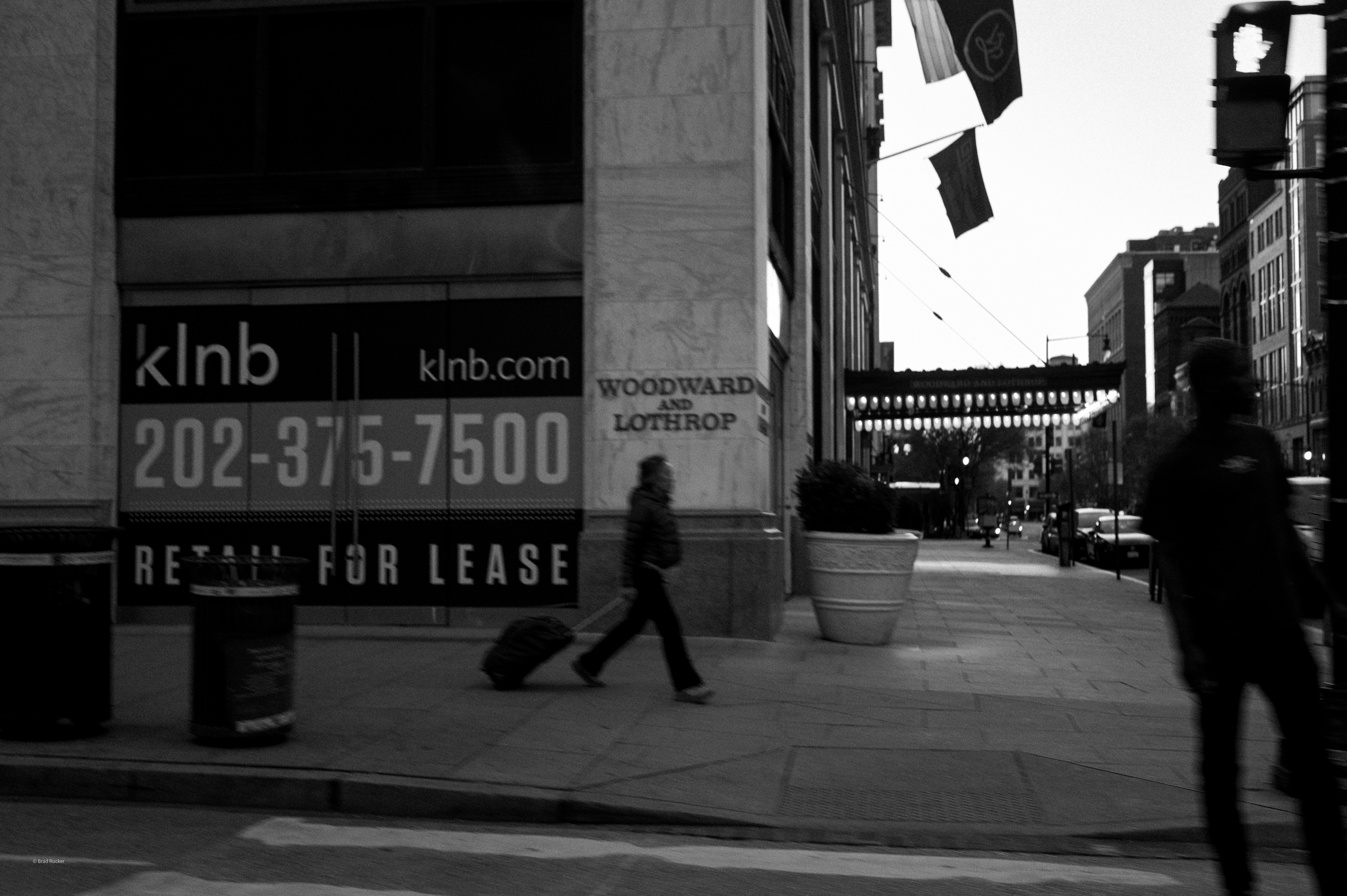 Person walks down a city street with a suitcase.