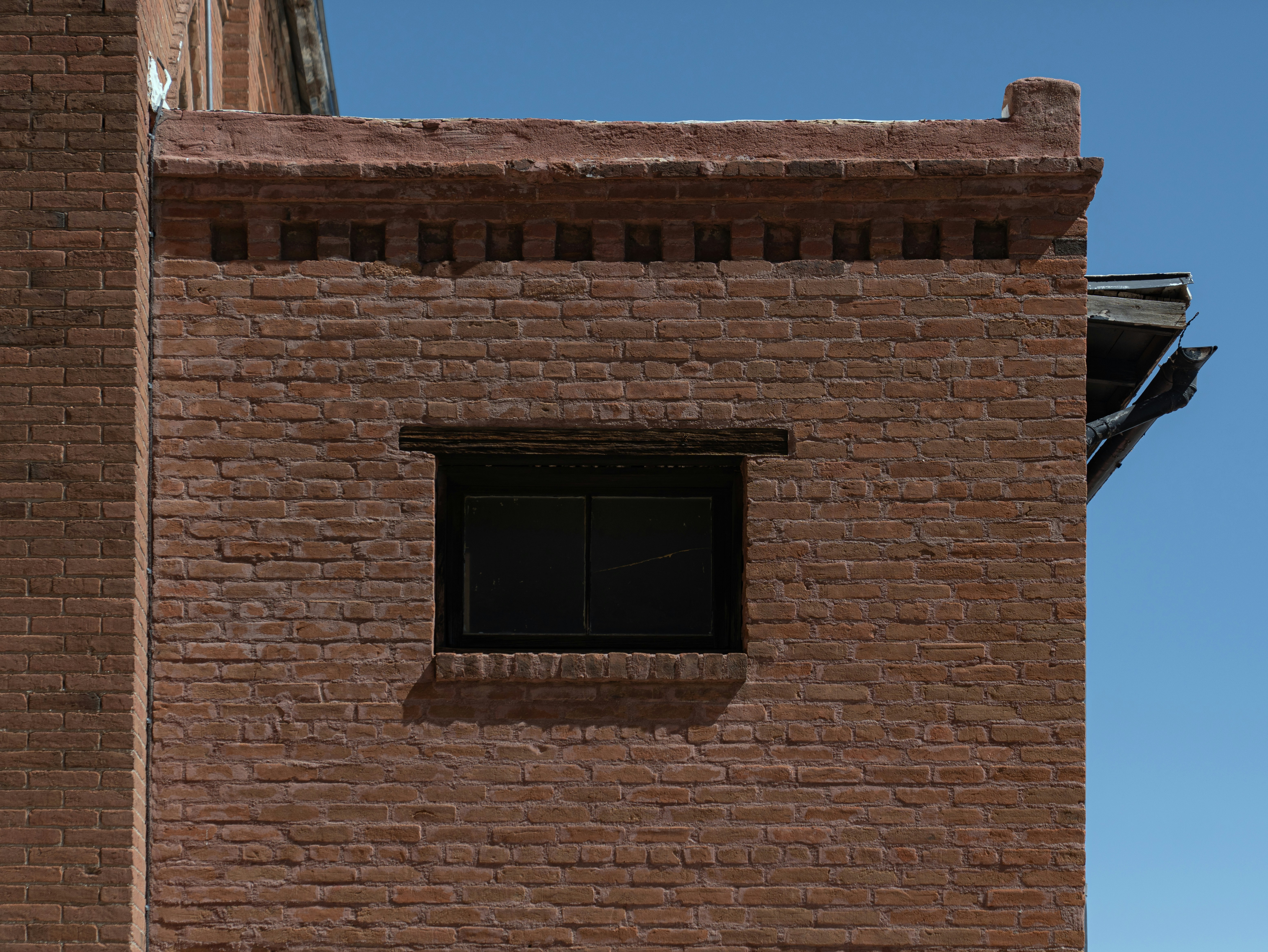 A red brick building with a dark window.