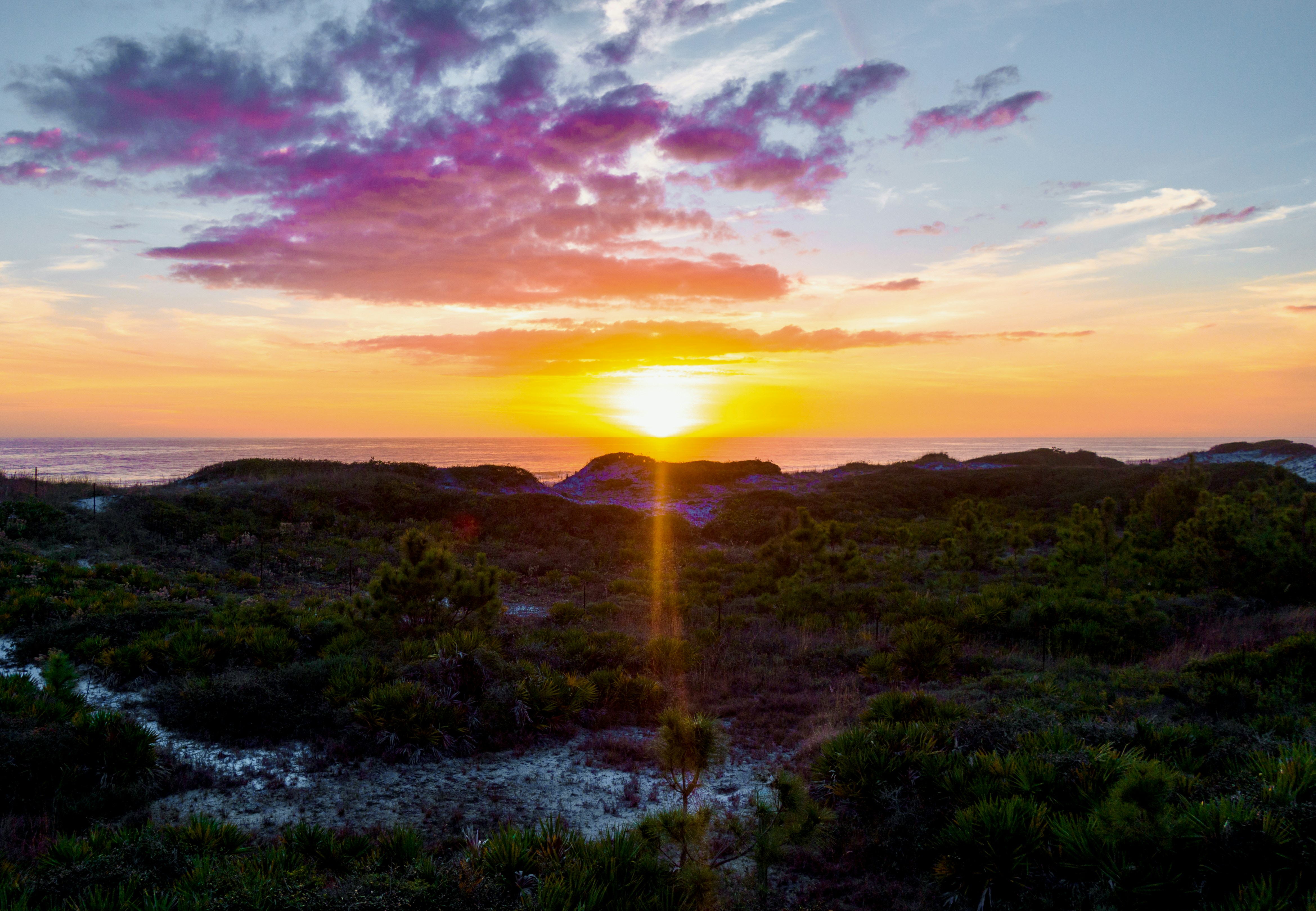 Sunset over a coastal landscape with colorful clouds