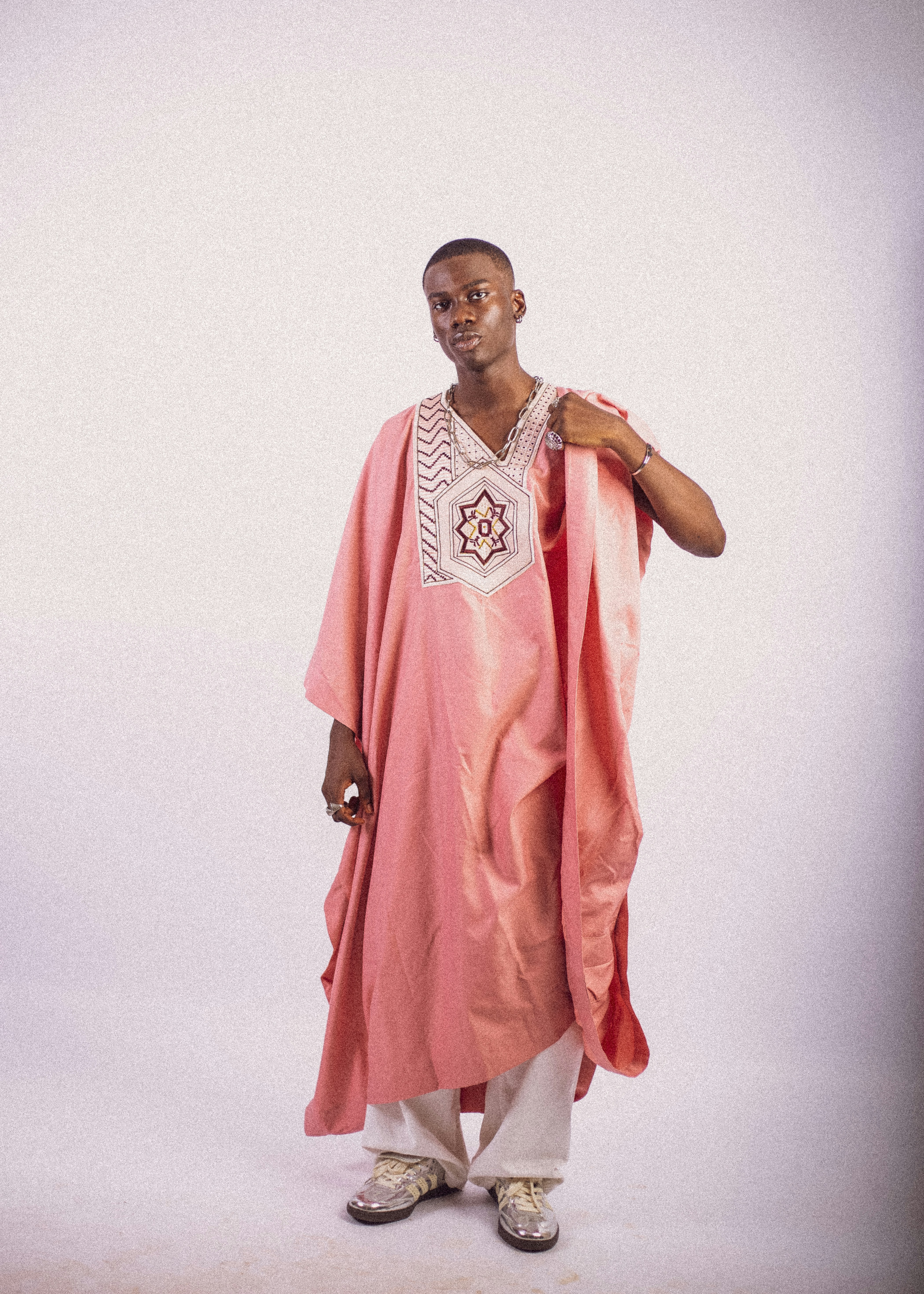Young man in a blush pink agbada with an embroidered chest panel