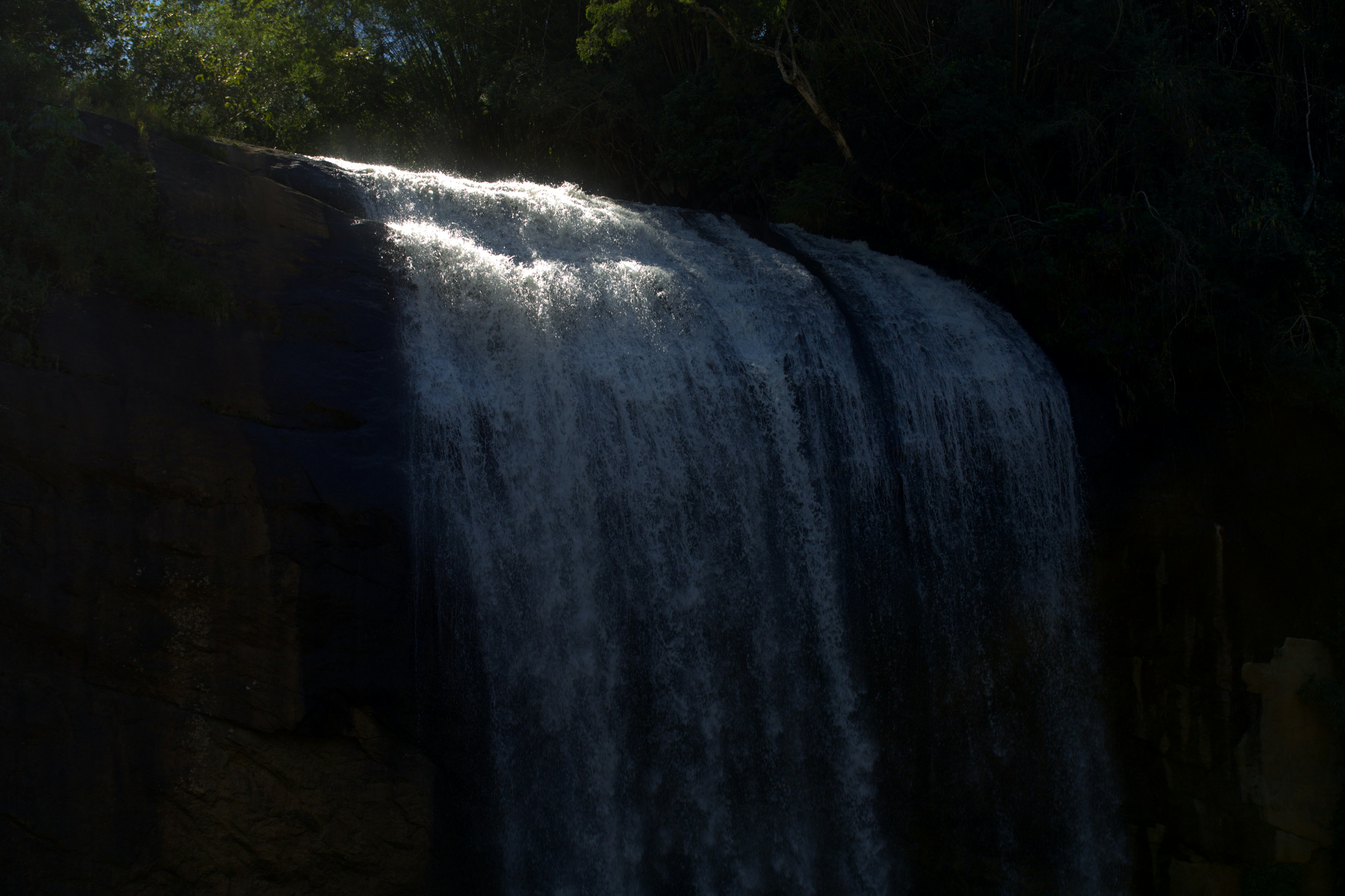 A dark waterfall cascades down a rocky cliff.