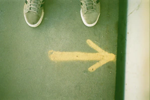 Feet standing next to a yellow arrow on ground