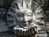 Stone sun face sculpture with outstretched hands