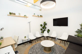 Modern waiting room with white chairs and plants.