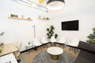 Modern waiting room with white chairs and plants.