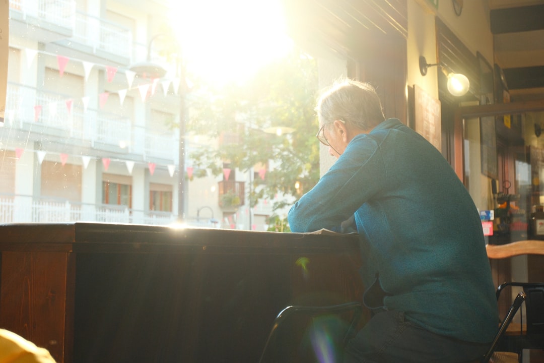 Man looking out a sunlit window indoors