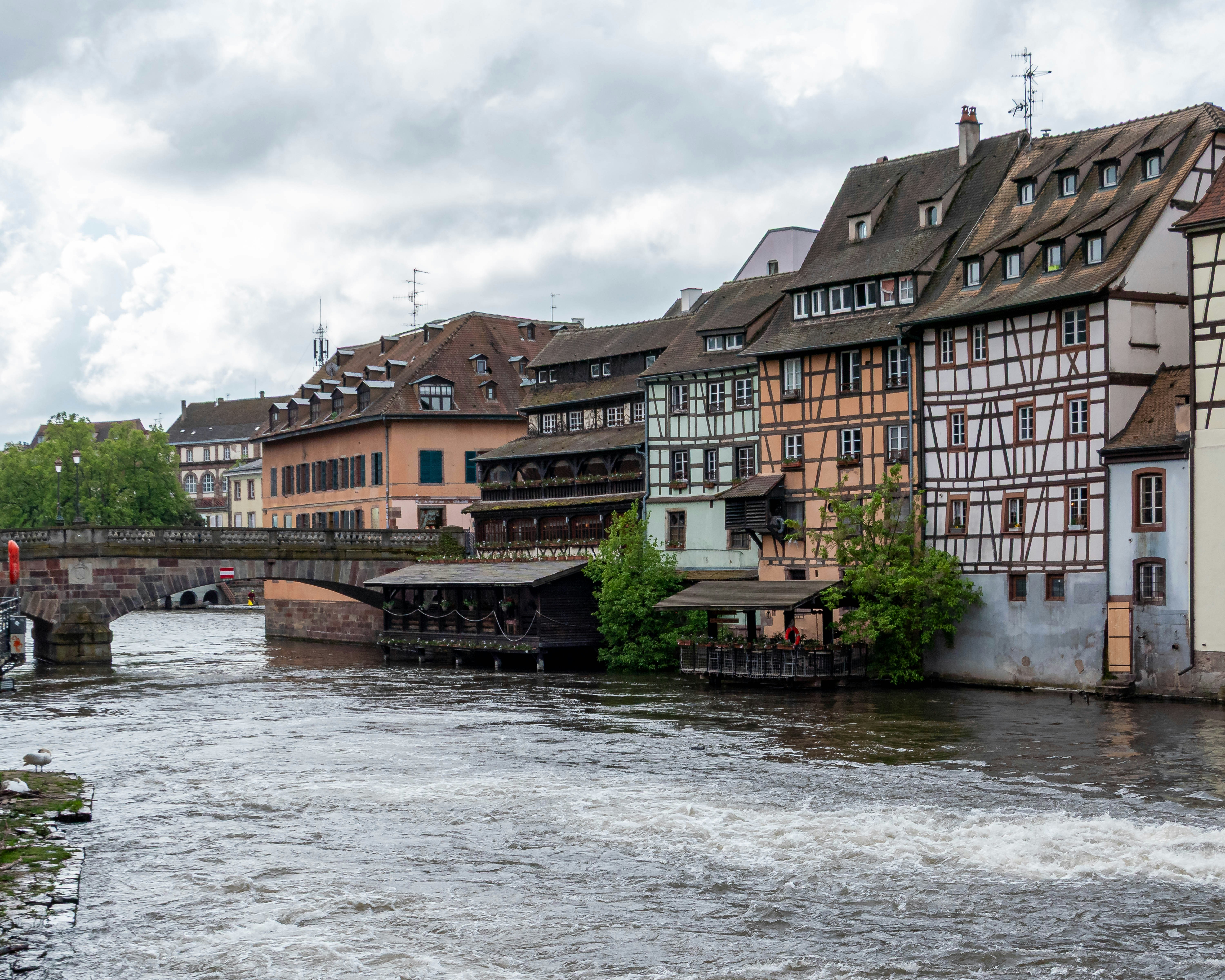 Half-timbered houses line a river canal with a bridge.