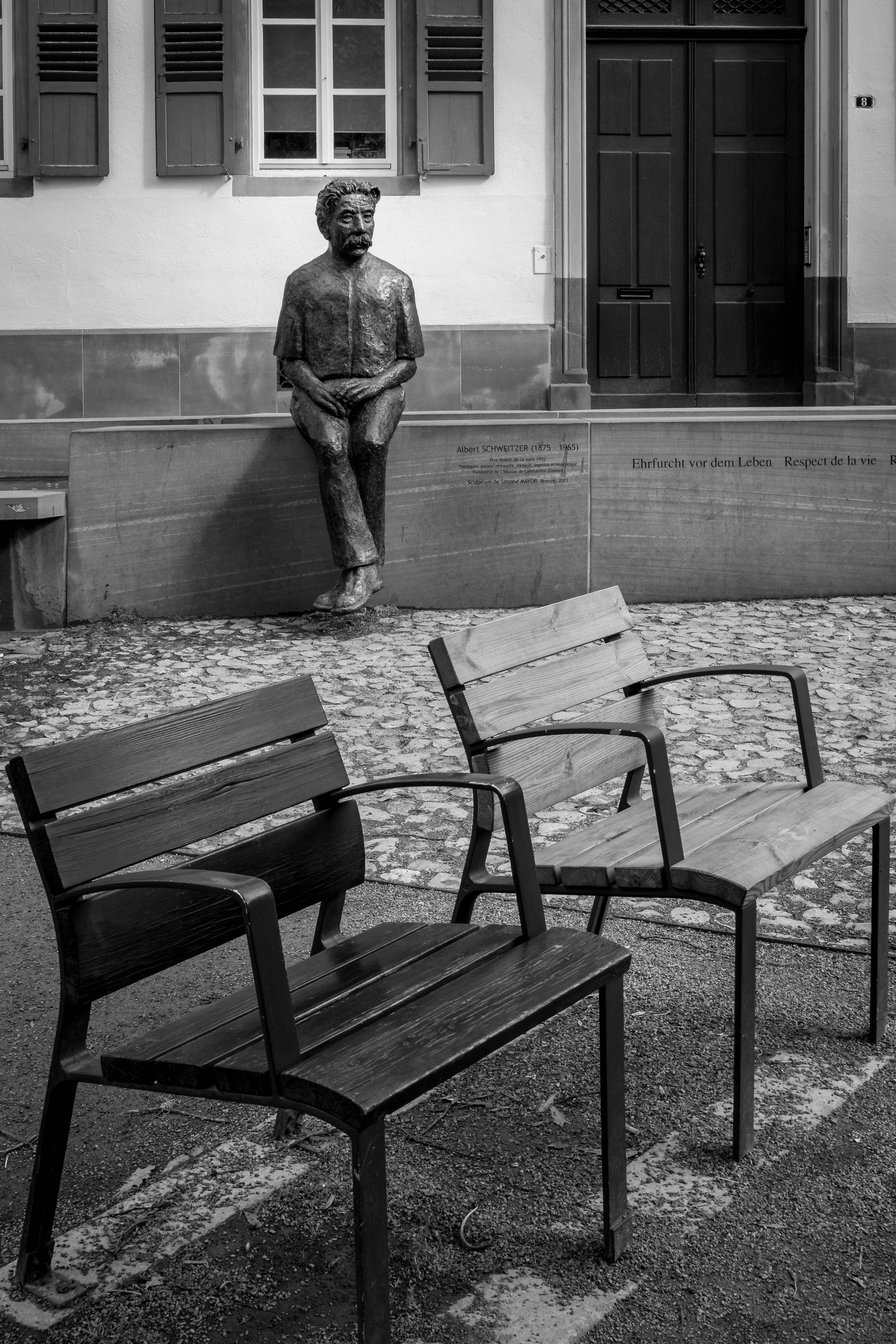Statue of a man sitting with two chairs