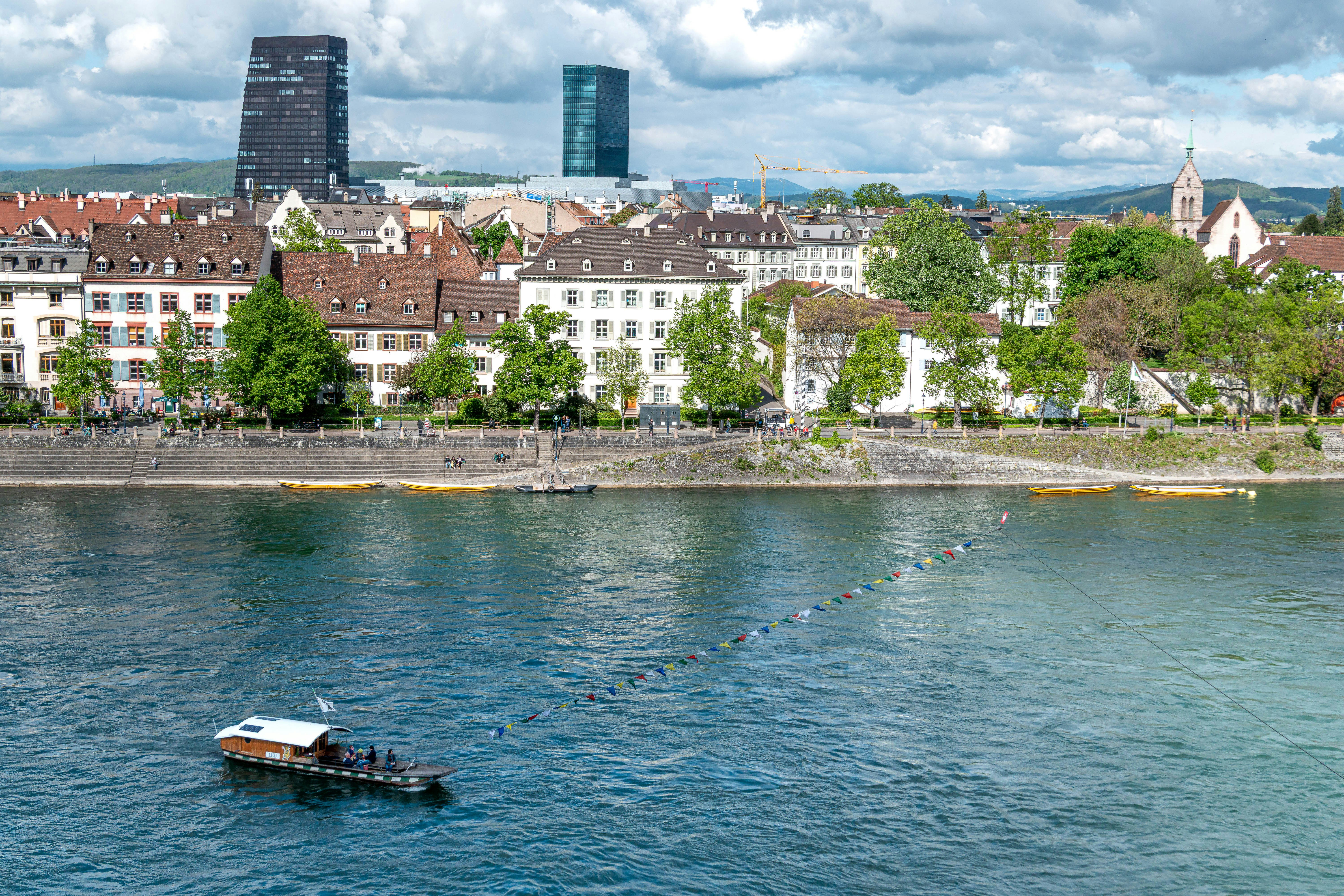 Boat on river with city skyline and cloudy sky