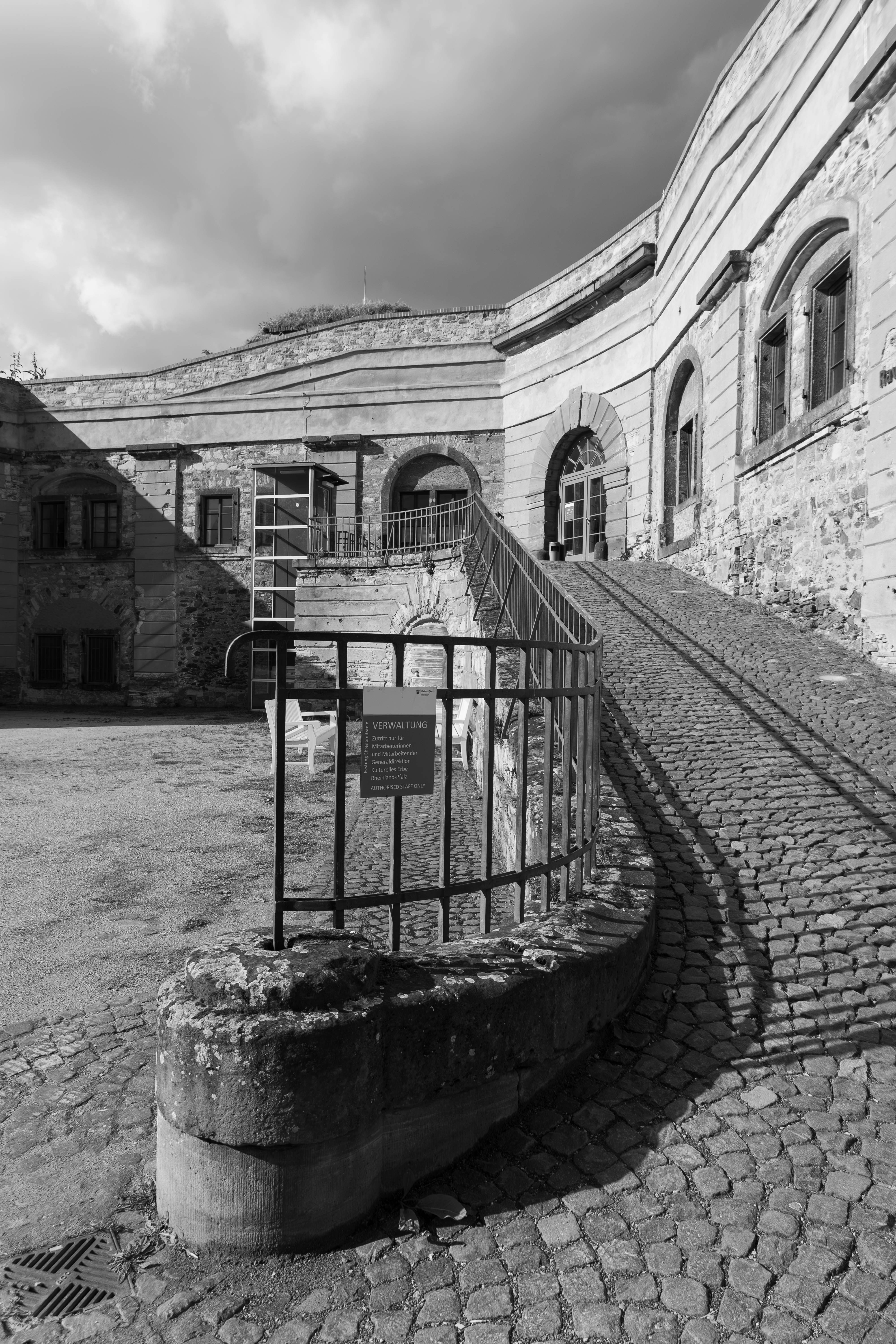 Old stone building with a cobblestone path and railing