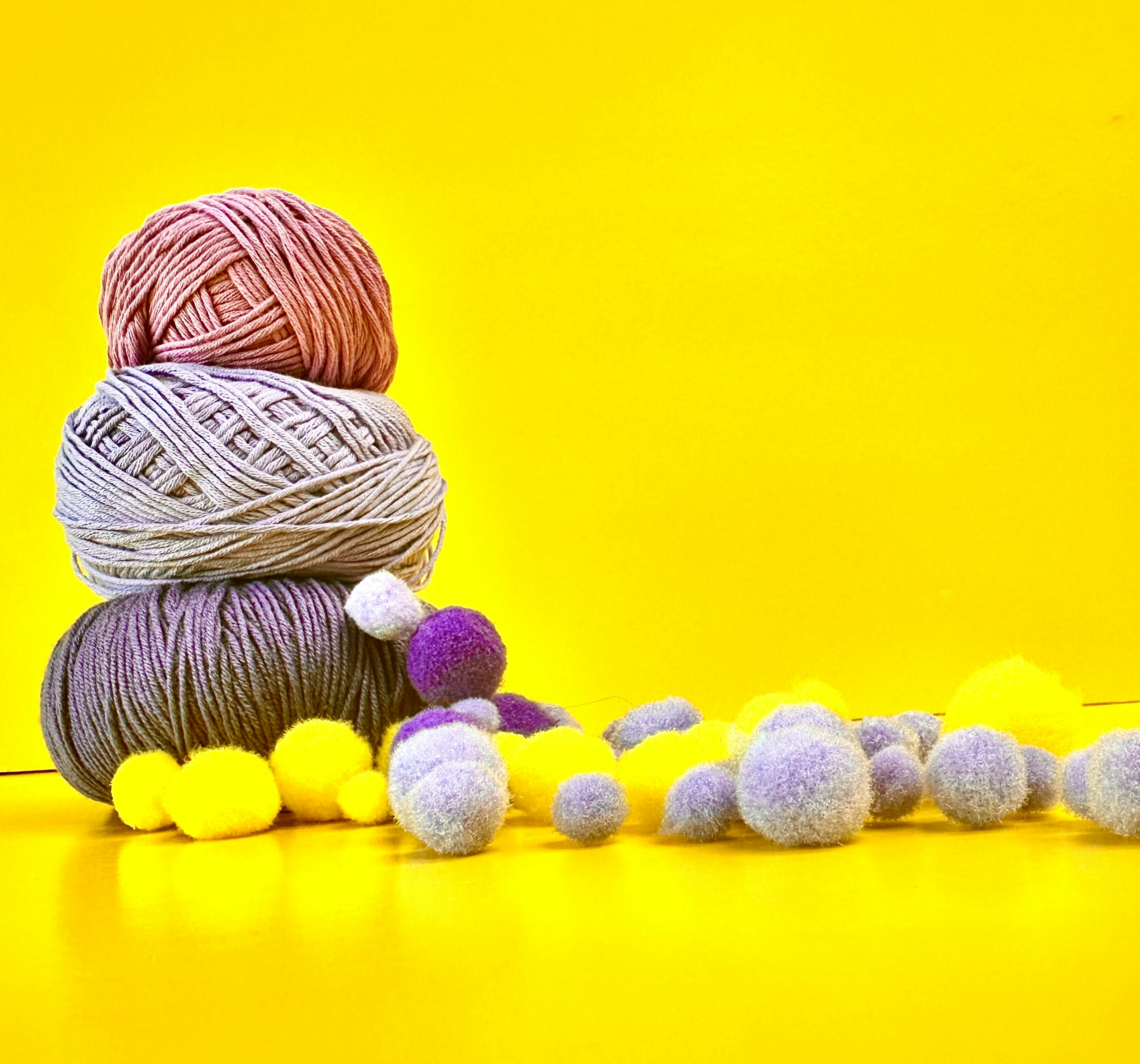 Três novelas de lã empilhadas com pompons