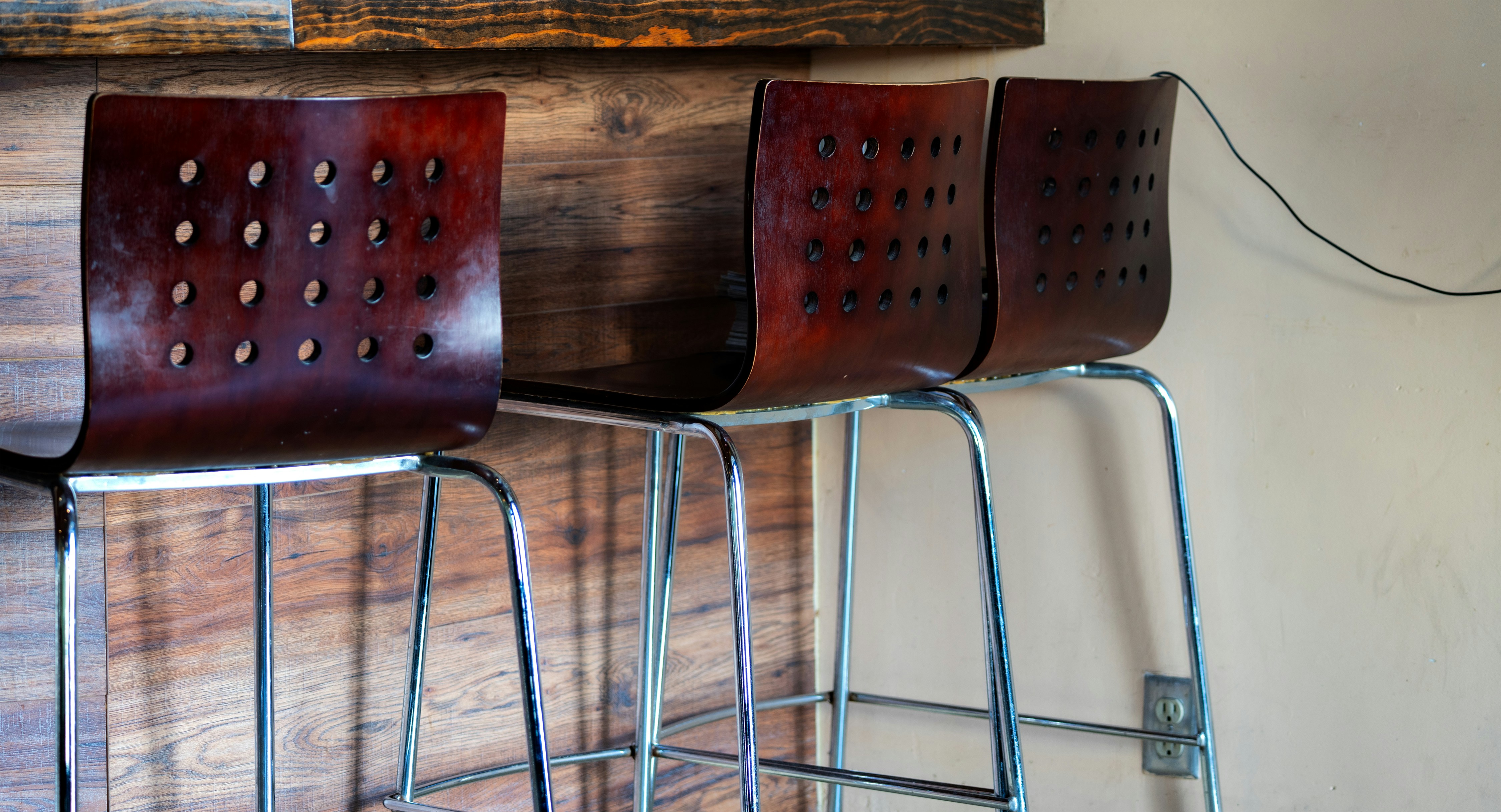 Three dark wooden bar stools with metal legs