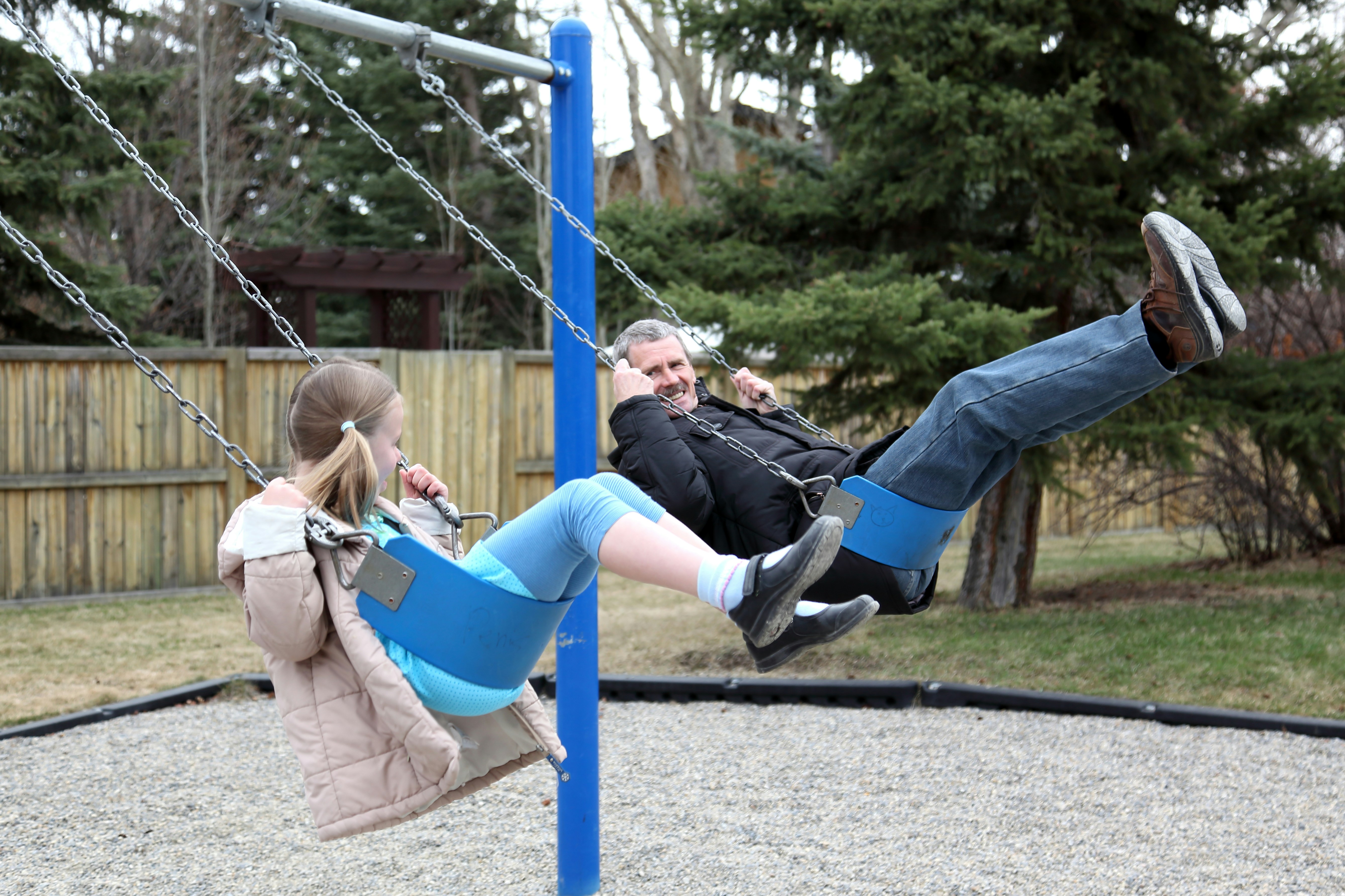 Padre e figlia che dondolano sulle altalene del parco giochi