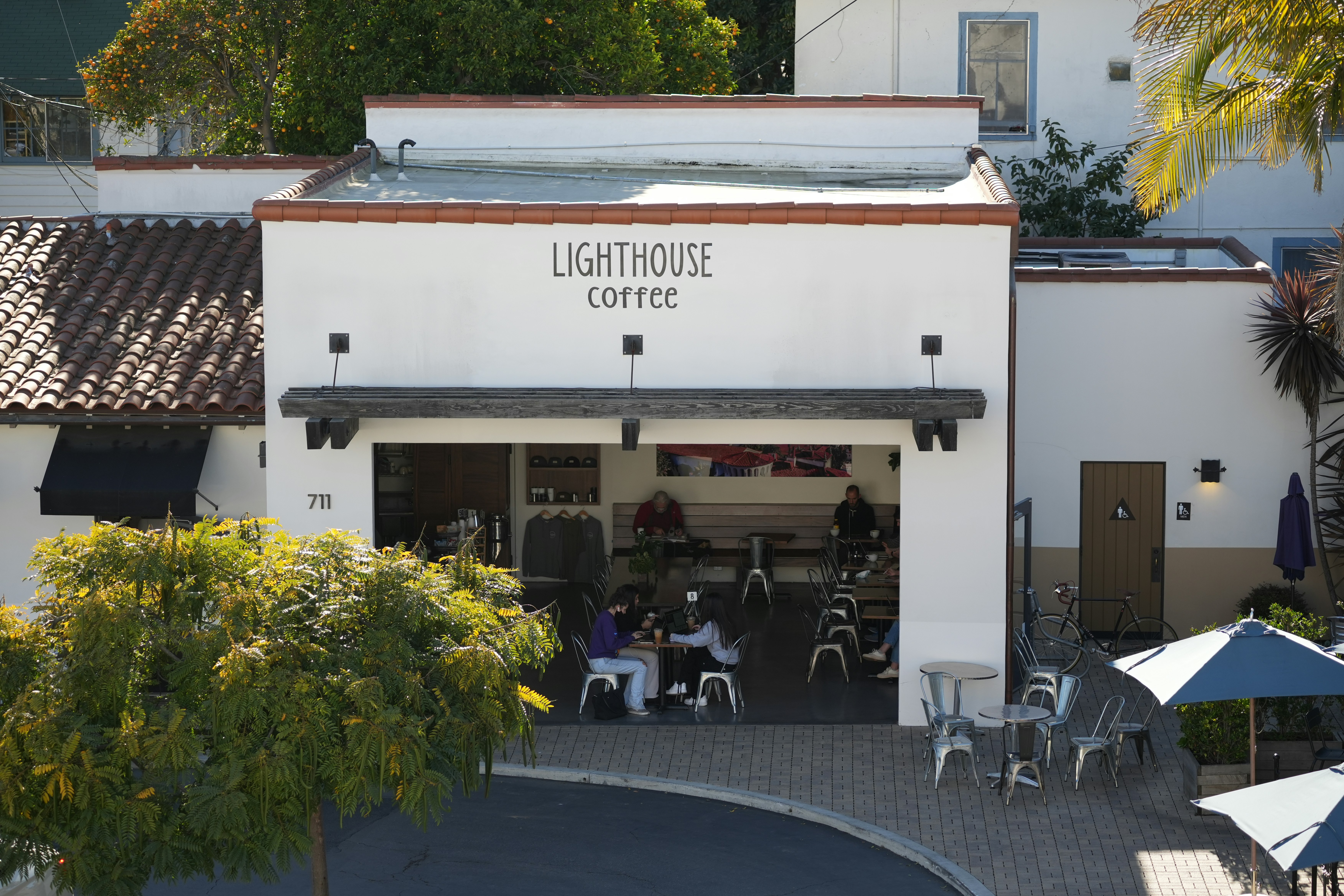 People sit at tables outside a coffee shop.