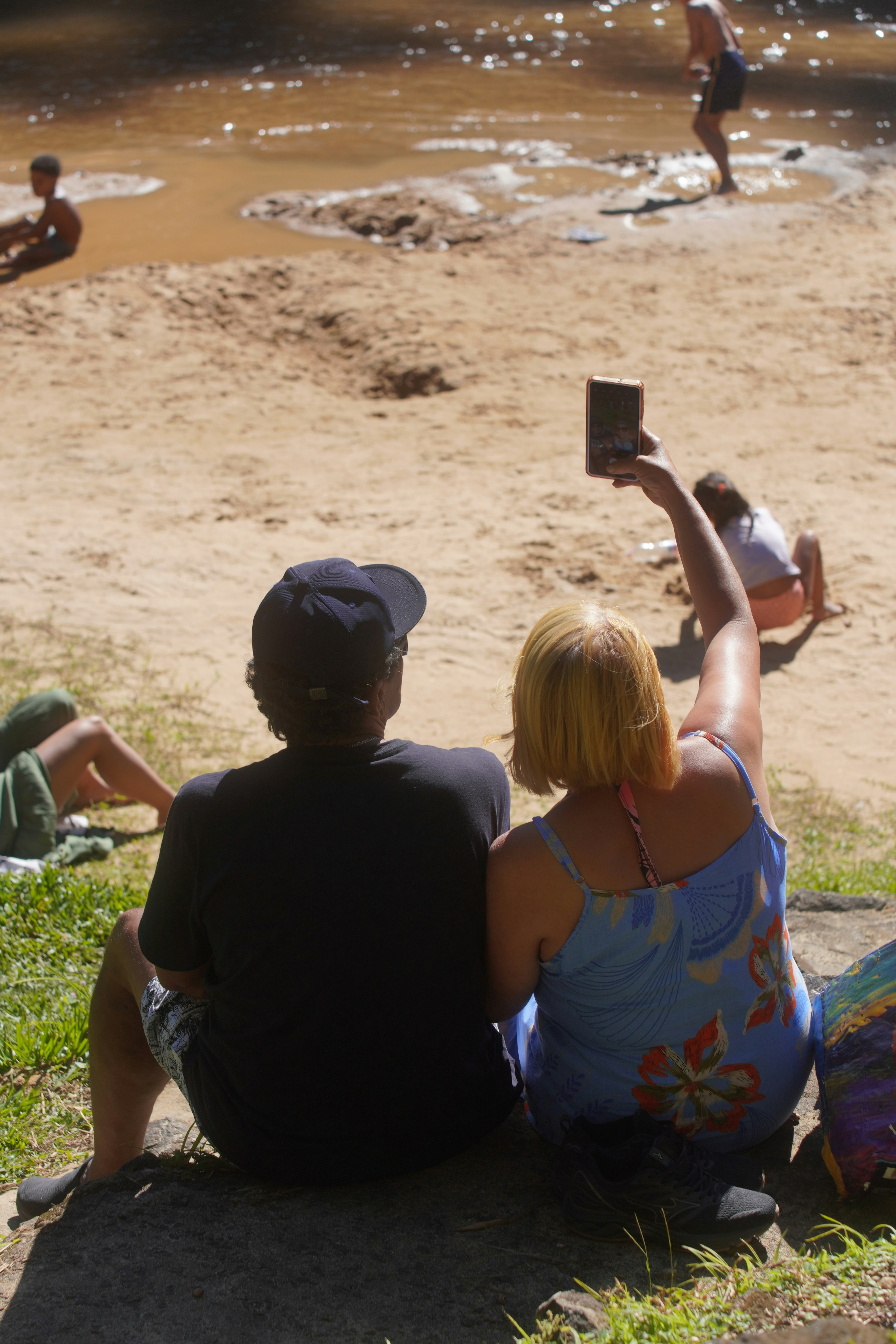 Couple taking a selfie by the muddy riverbank.