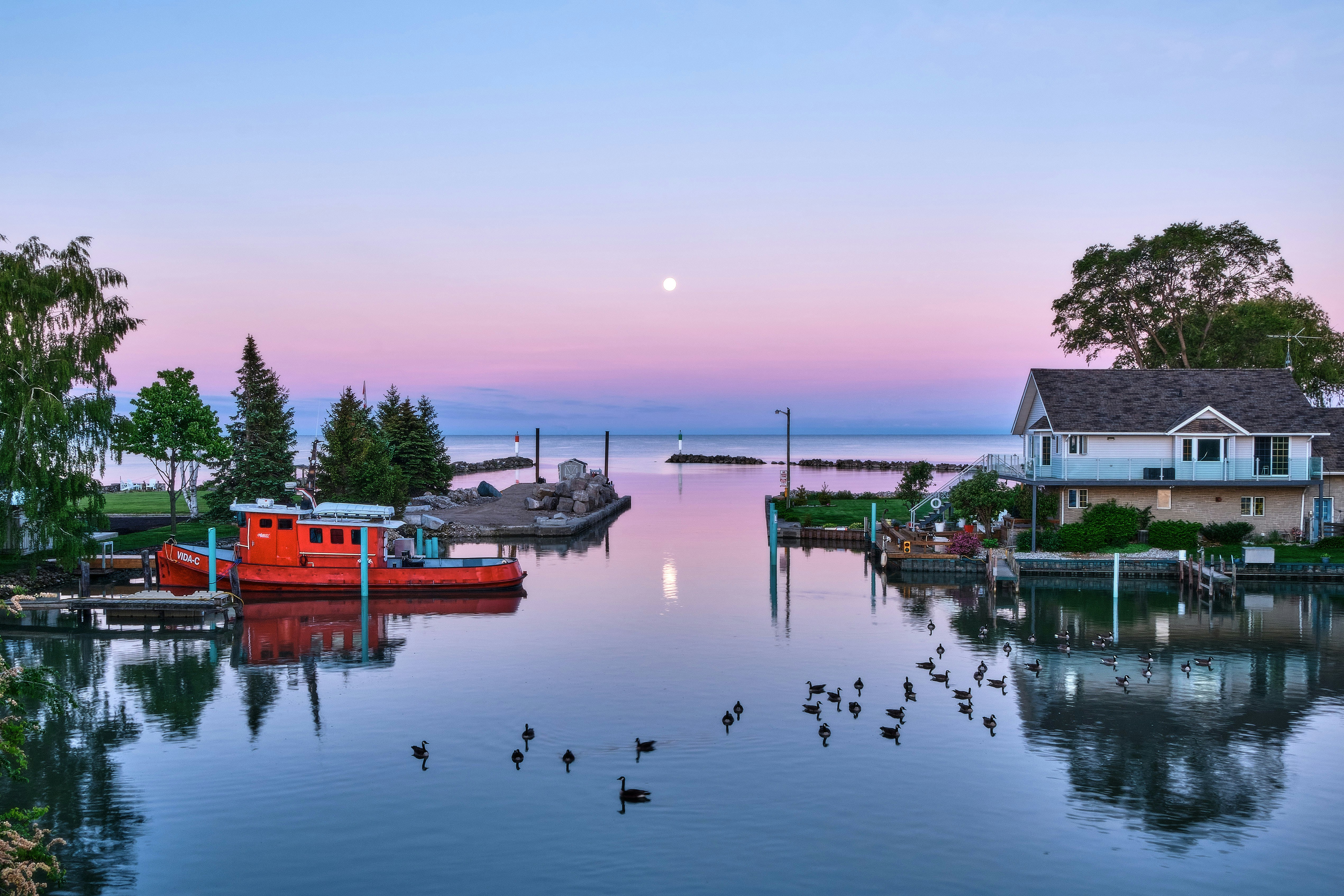 Calm waterway with boats at pastel sunset
