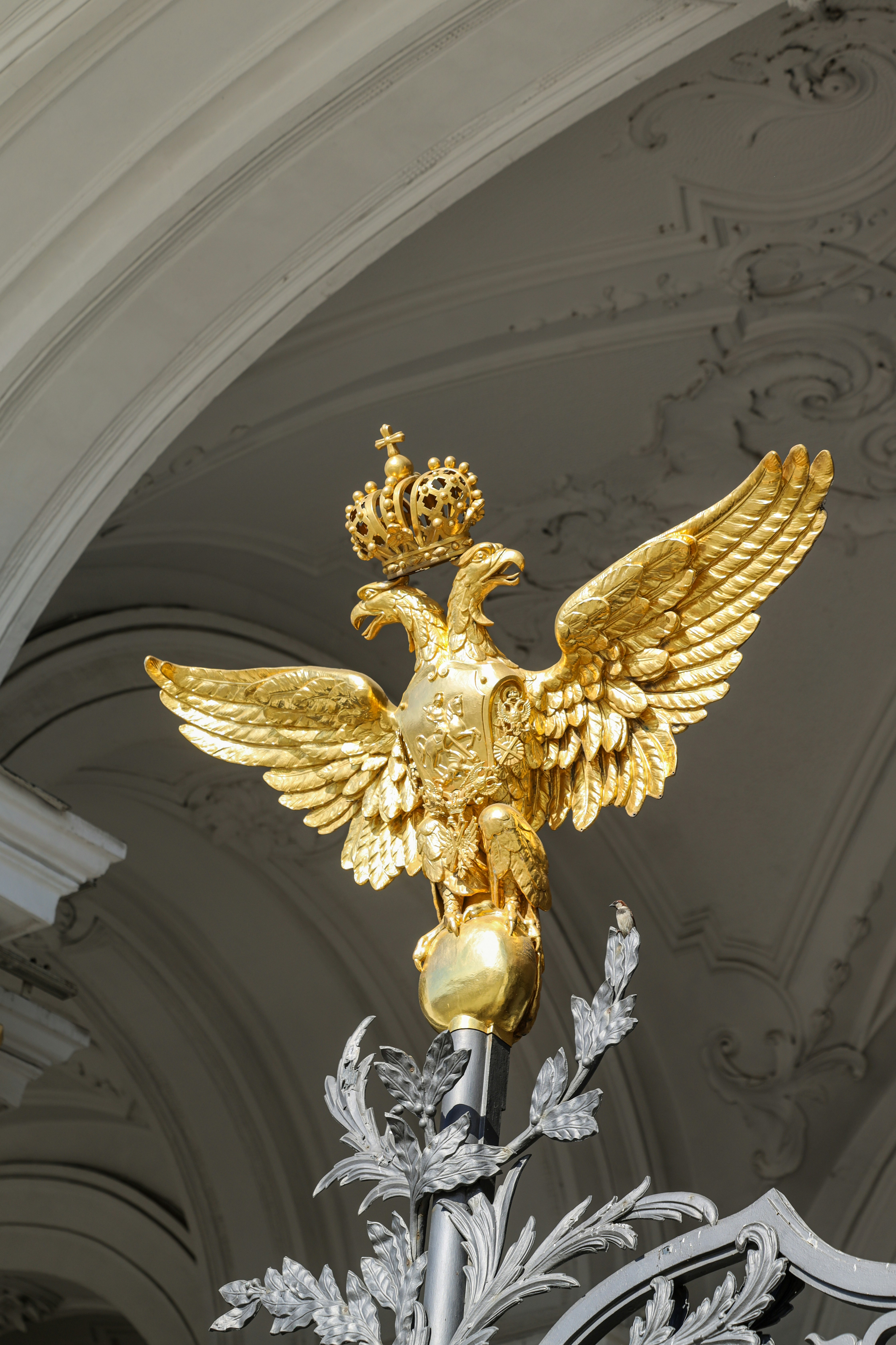 Águila bicéfala dorada con corona en la parte superior del globo