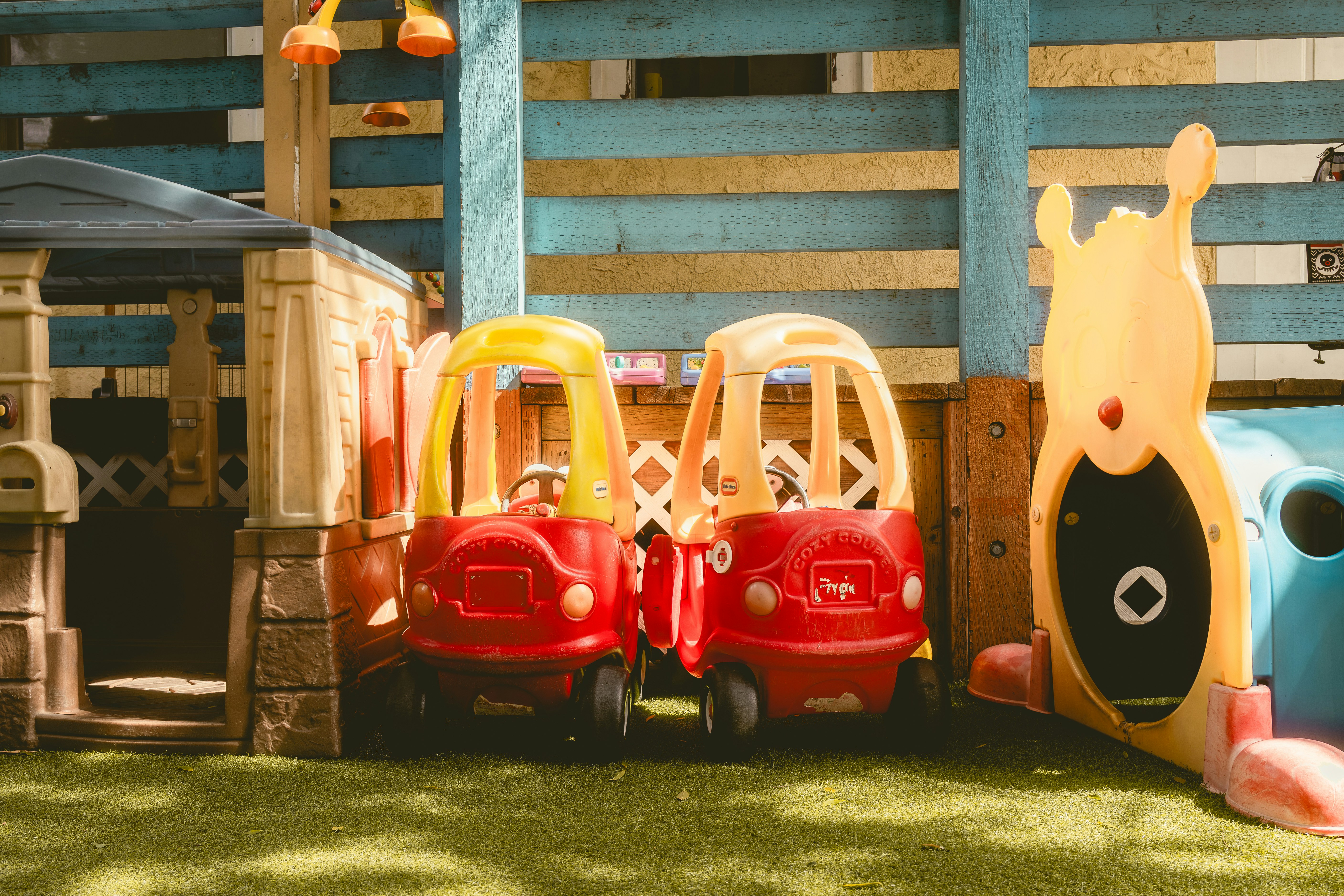 Two red toy cars parked on a playground