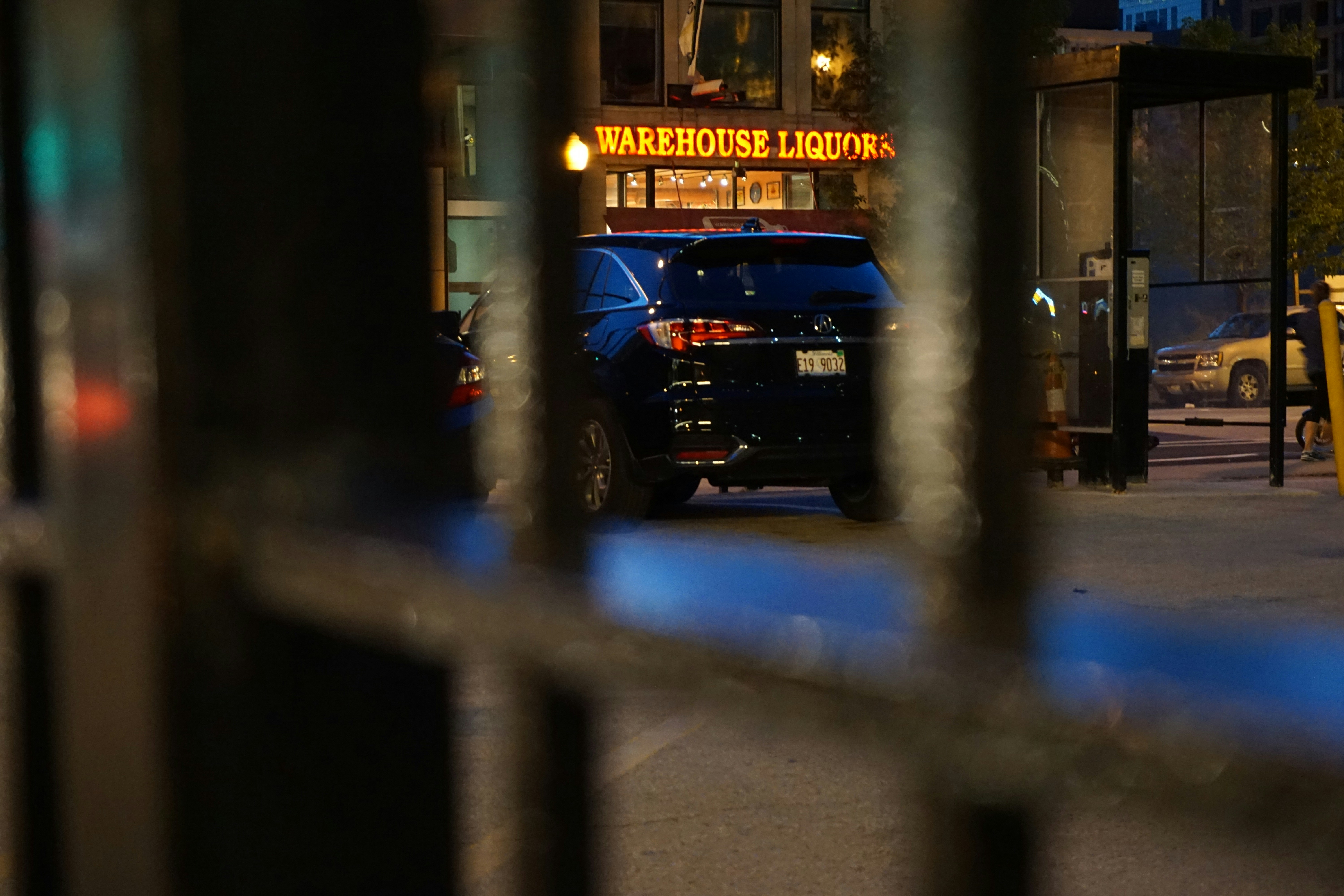A blurred image of police tape or a police vehicle in the background, with a focused image of an official looking through documents, symbolizing investigation.