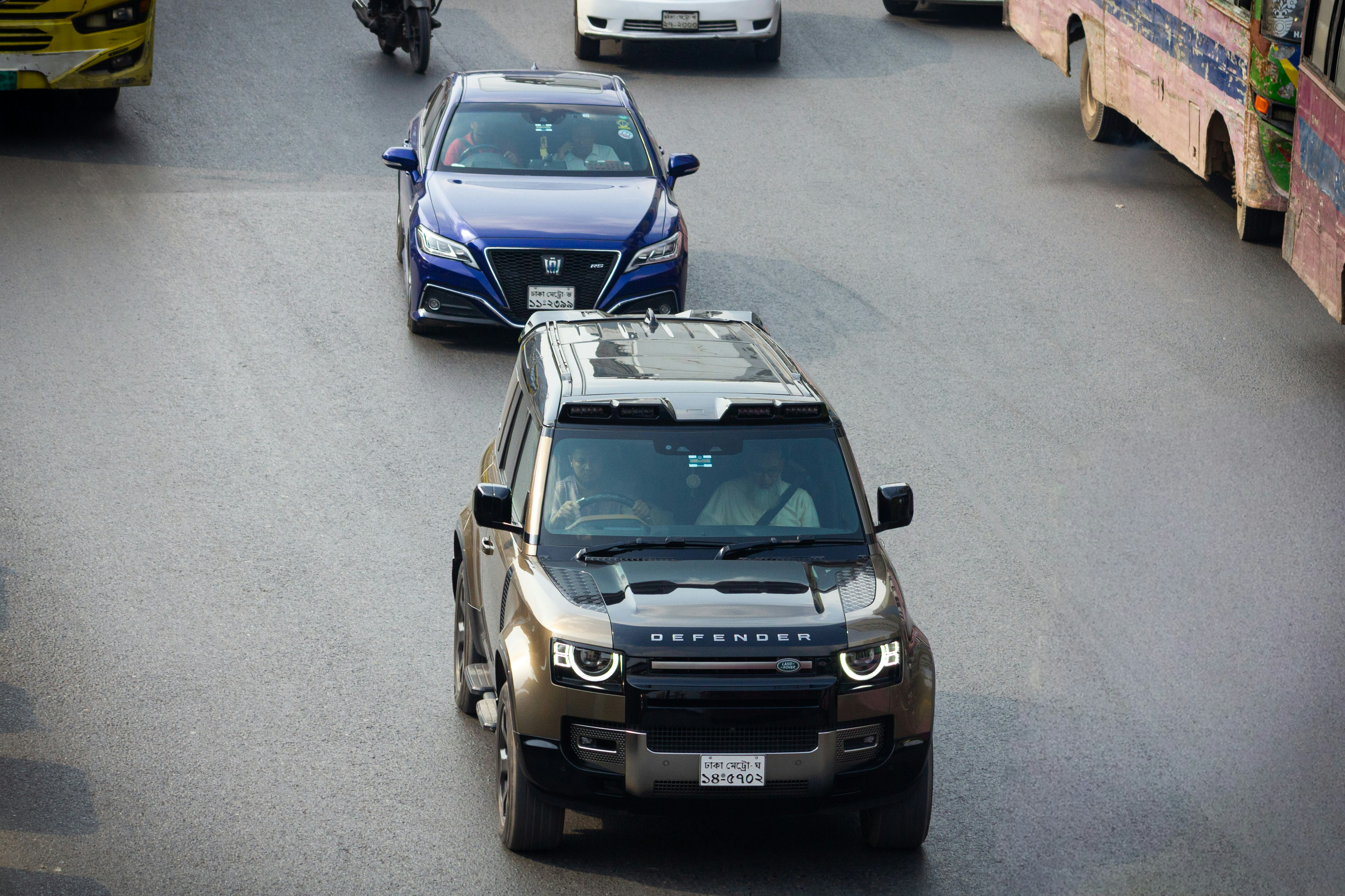 Two cars driving on a busy city street.