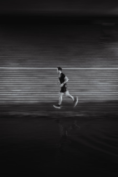 Man running laps on a floodlit track at night