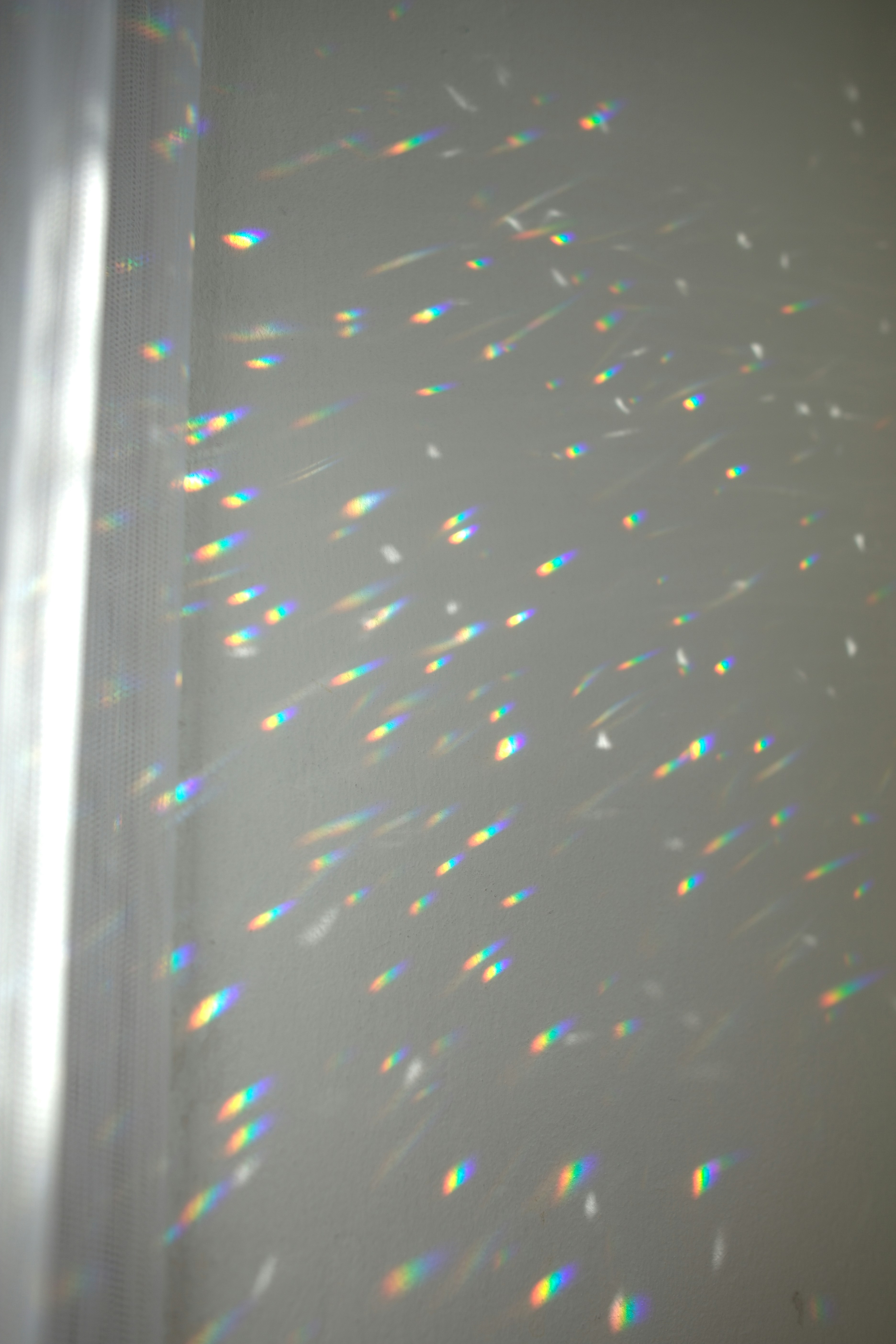 Riflessi di luce arcobaleno su una parete bianca.