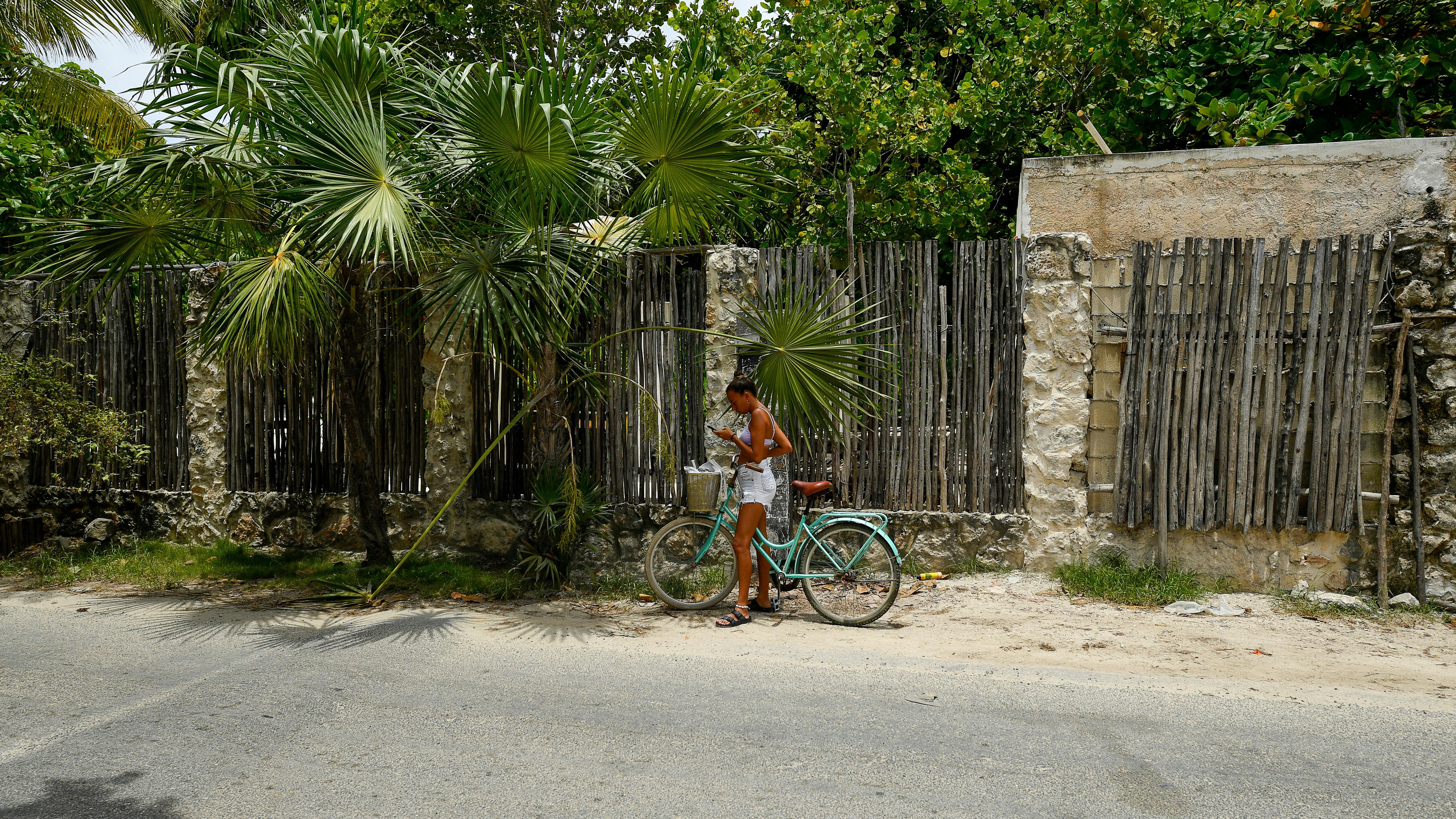 Woman with bicycle by a rustic wooden fence
