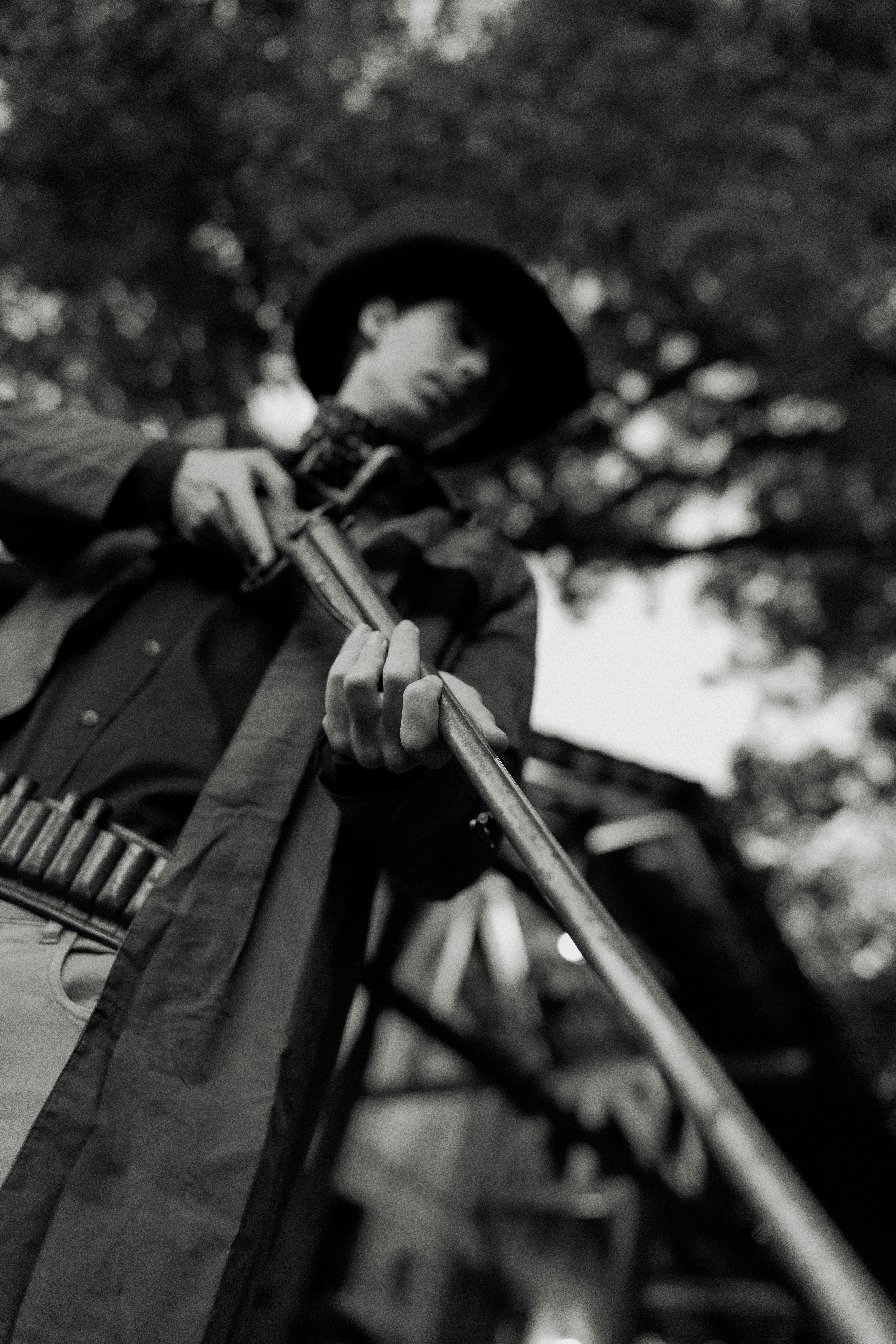 Man in cowboy hat loads rifle outdoors