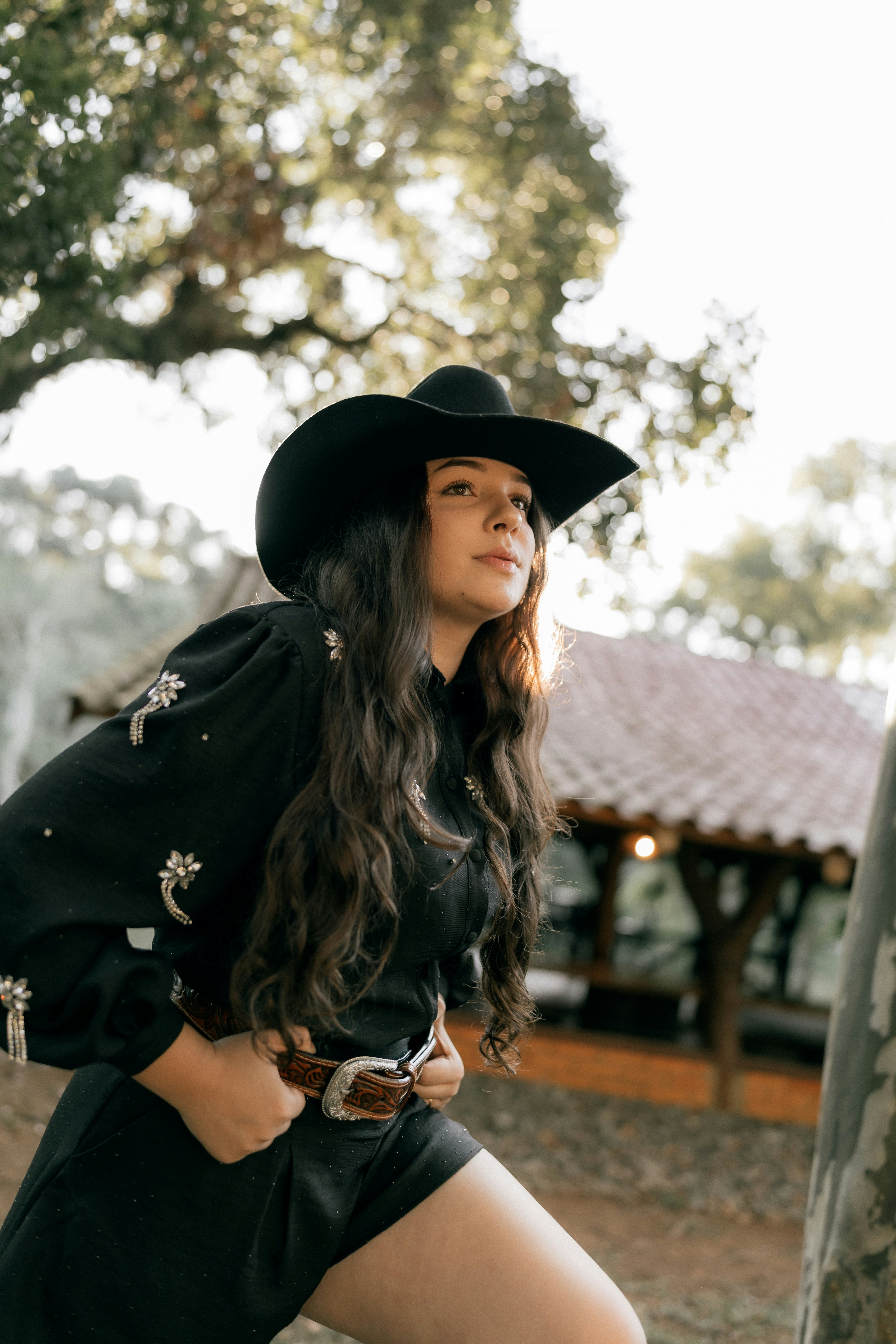 Woman in black cowboy hat and outfit outdoors