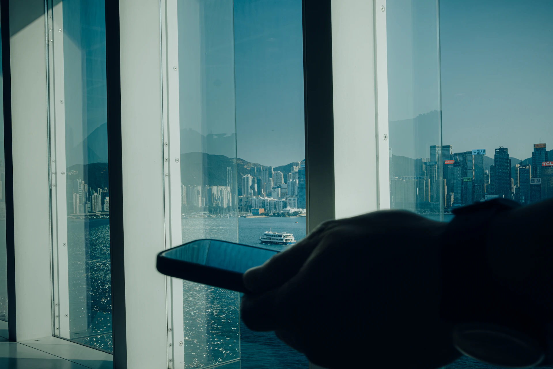 Hand holding smartphone with city skyline reflection