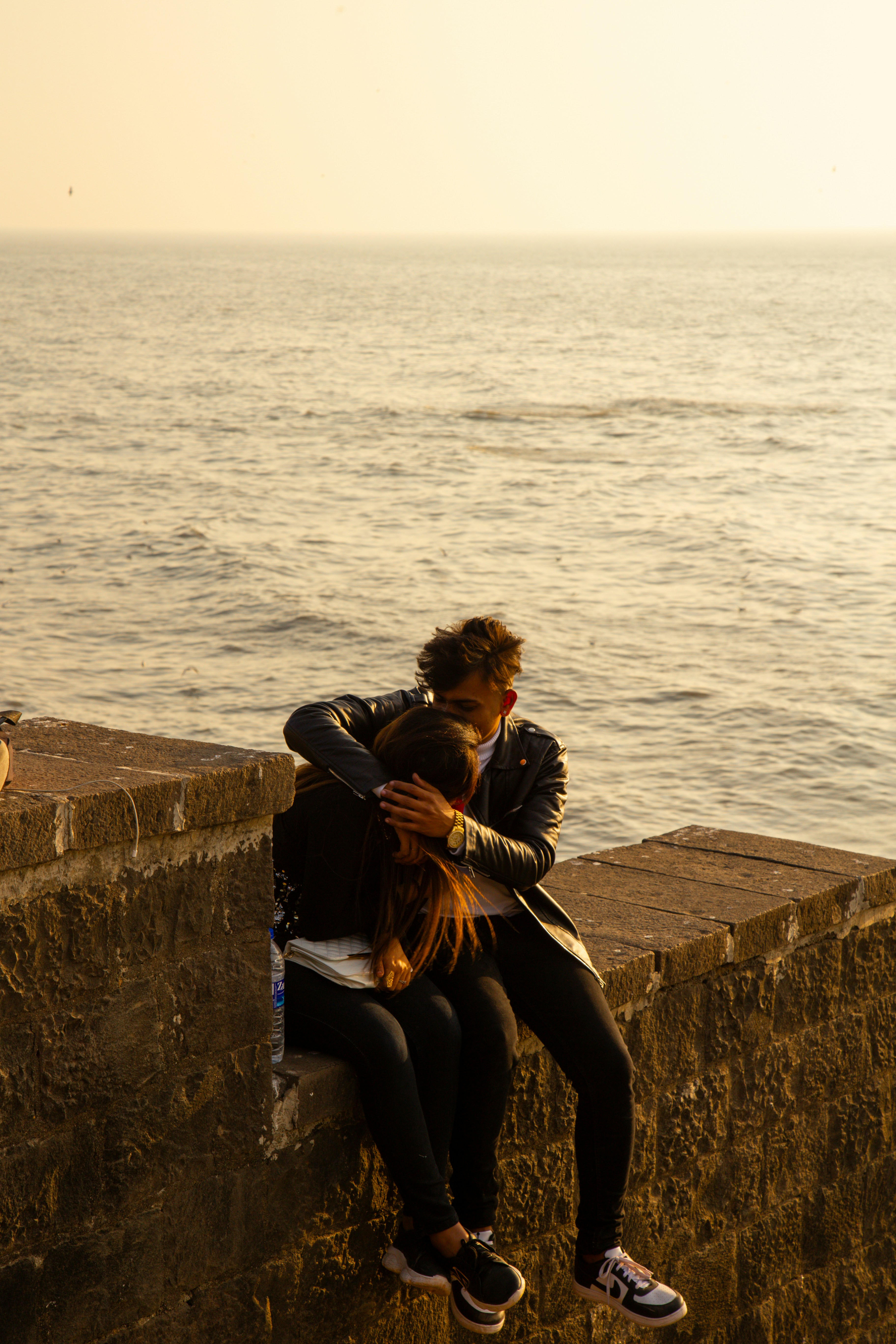 Pareja abrazándose en una pared junto al mar