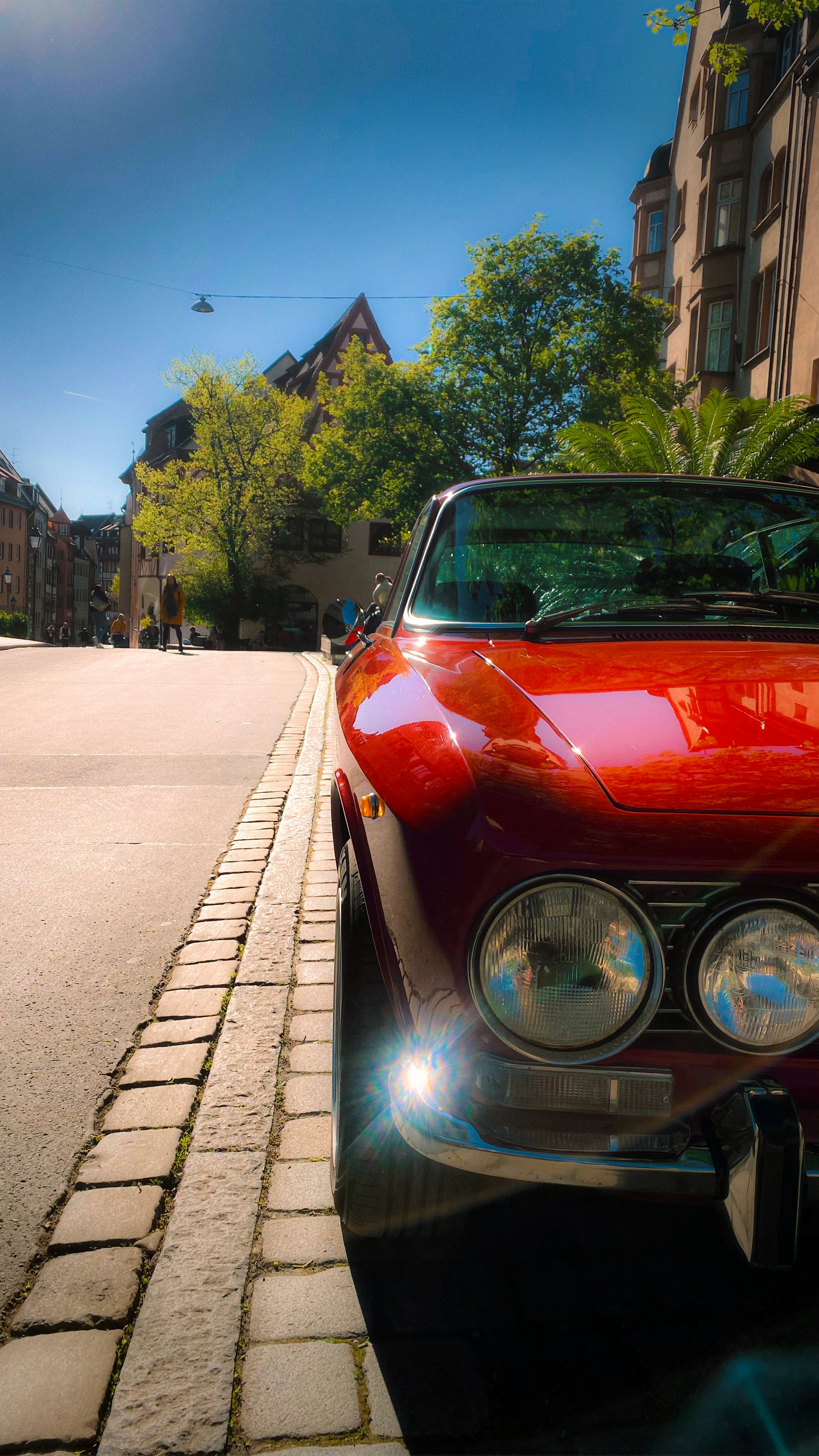 Auto d'epoca rossa parcheggiata su una strada di ciottoli.