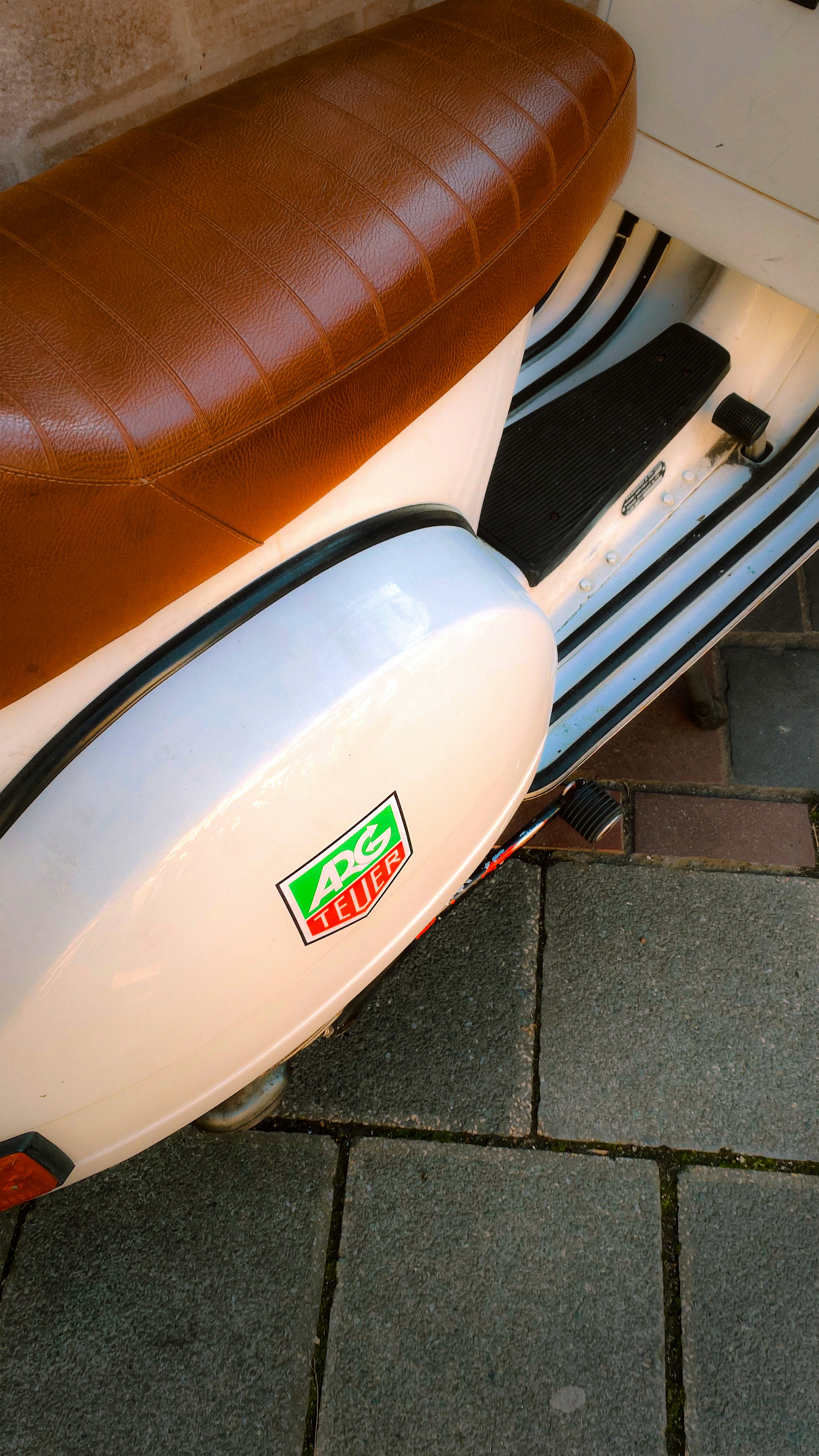 Scooter bianco con sedile marrone e logo con il tag Heuer.