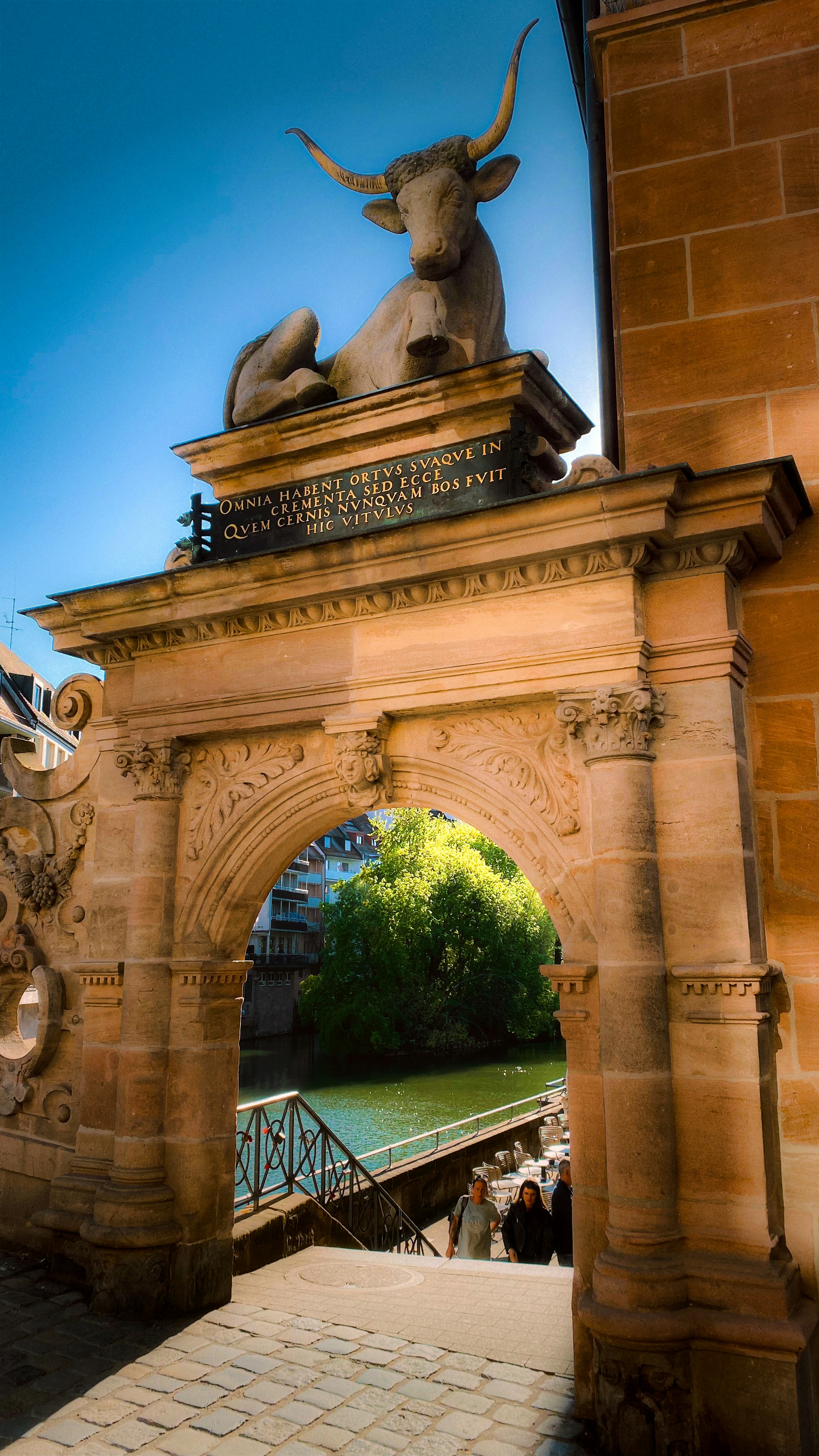 Arco in pietra con scultura di tori si affaccia su fiume e fiume.