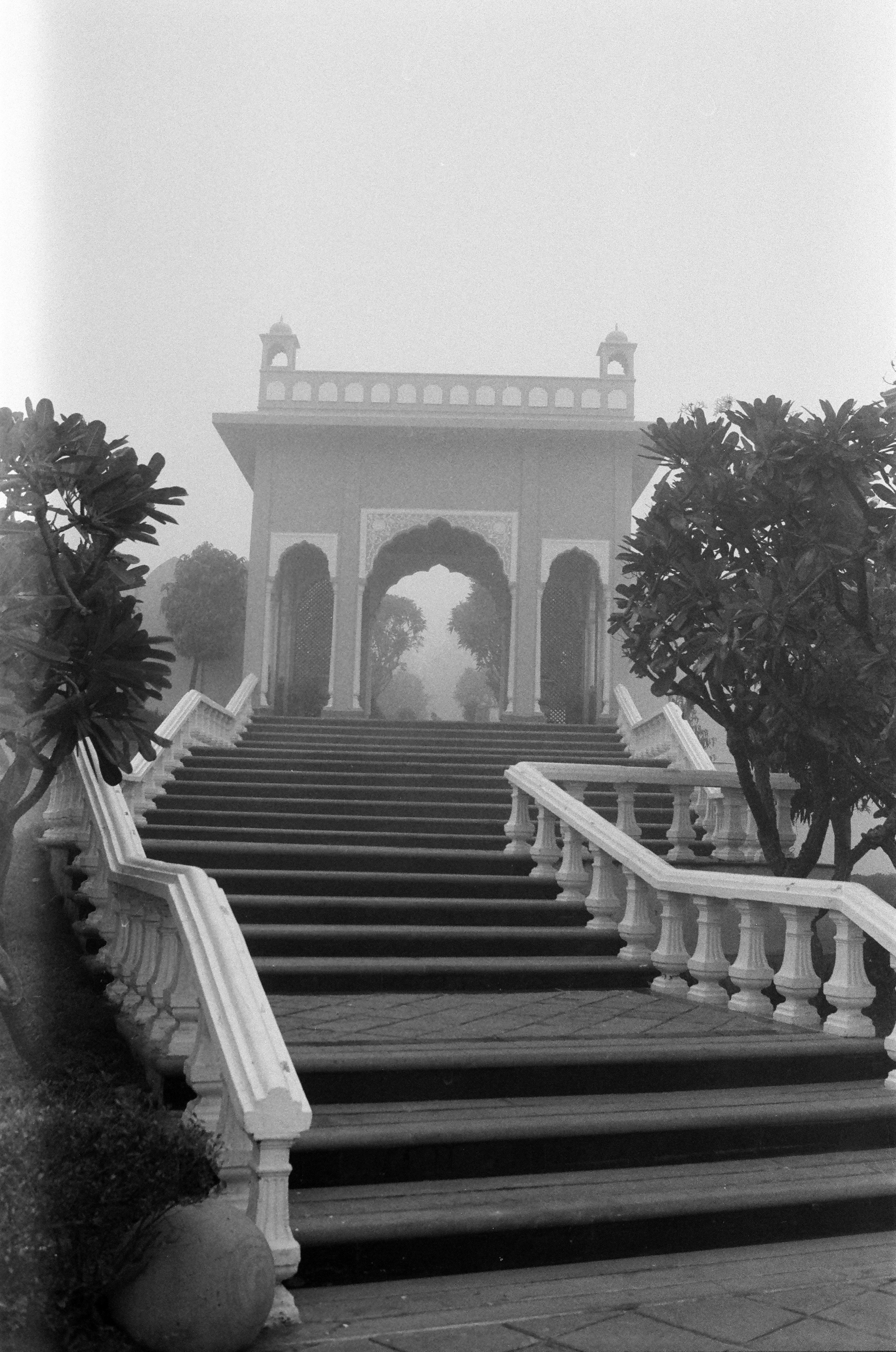 Grand staircase leading to an arched gateway in fog