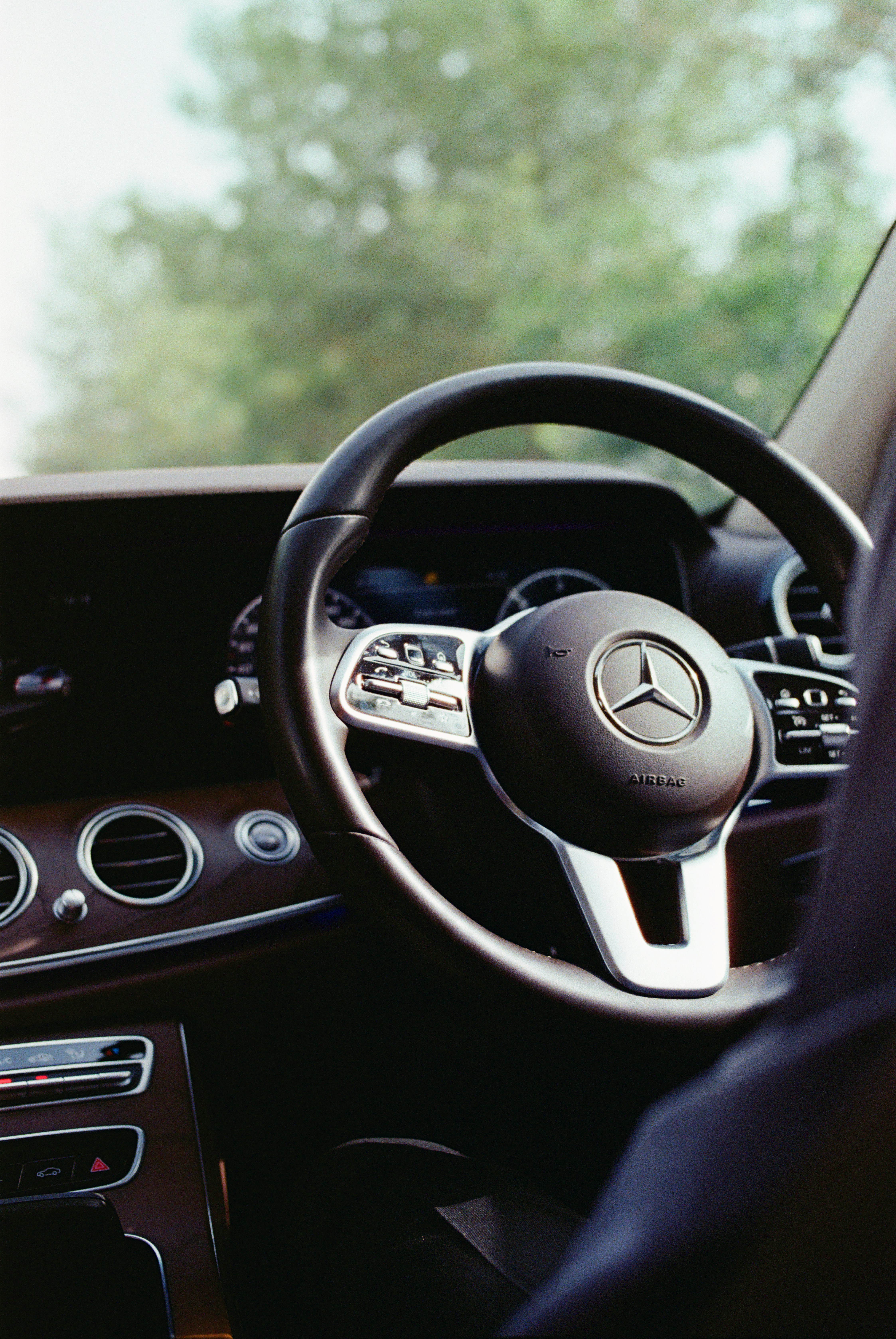 Interior of a luxury car with a mercedes-benz steering wheel.