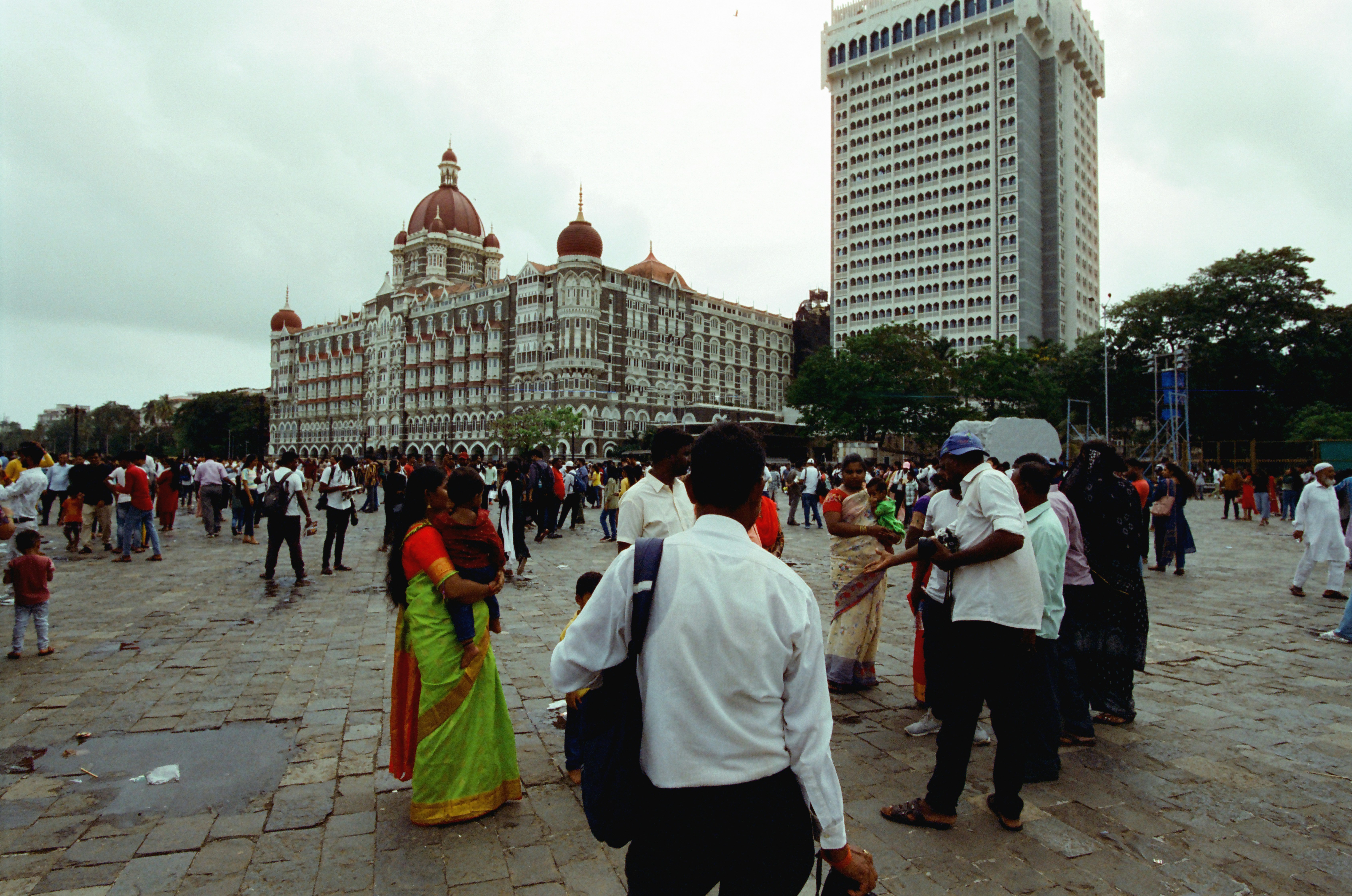 A diverse crowd of people from various Indian religions and cultures, smiling and interacting peacefully in a public square. Shot with warm lighting.