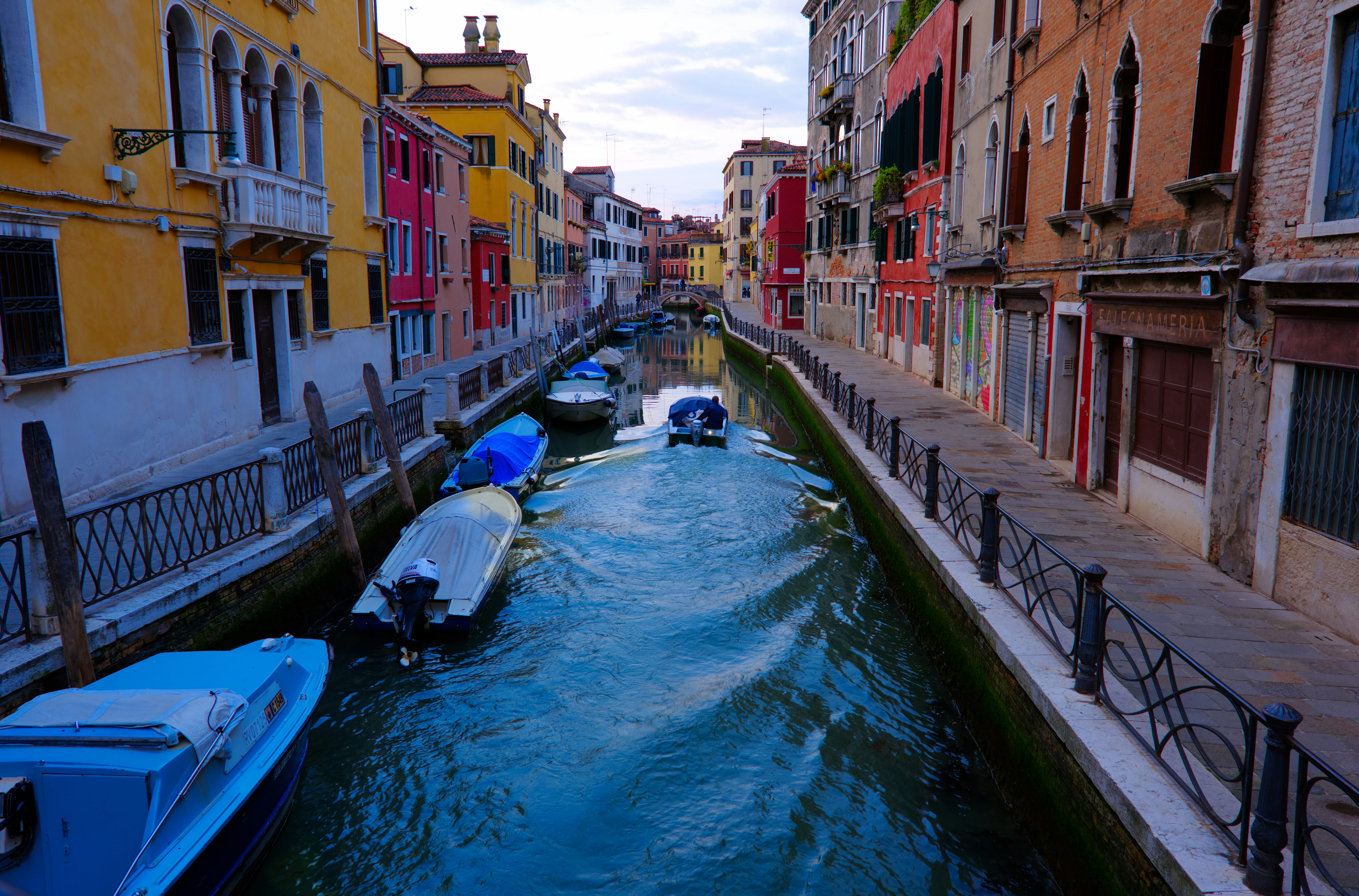 Boats navigate a narrow canal lined with colorful buildings.